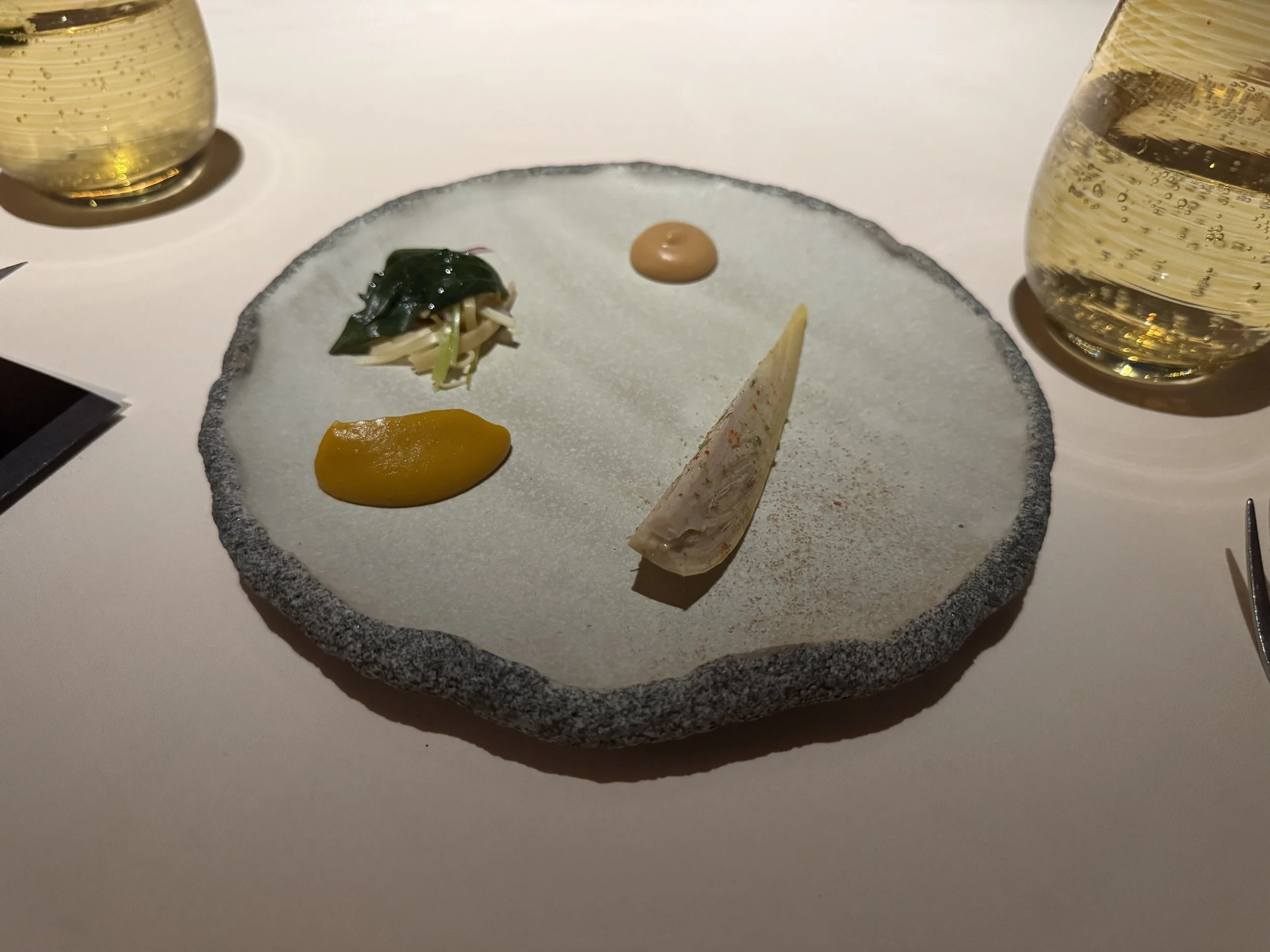 sliced banana heart on a stone plate next to pumpkin puree, sauce, and pickled vegetables