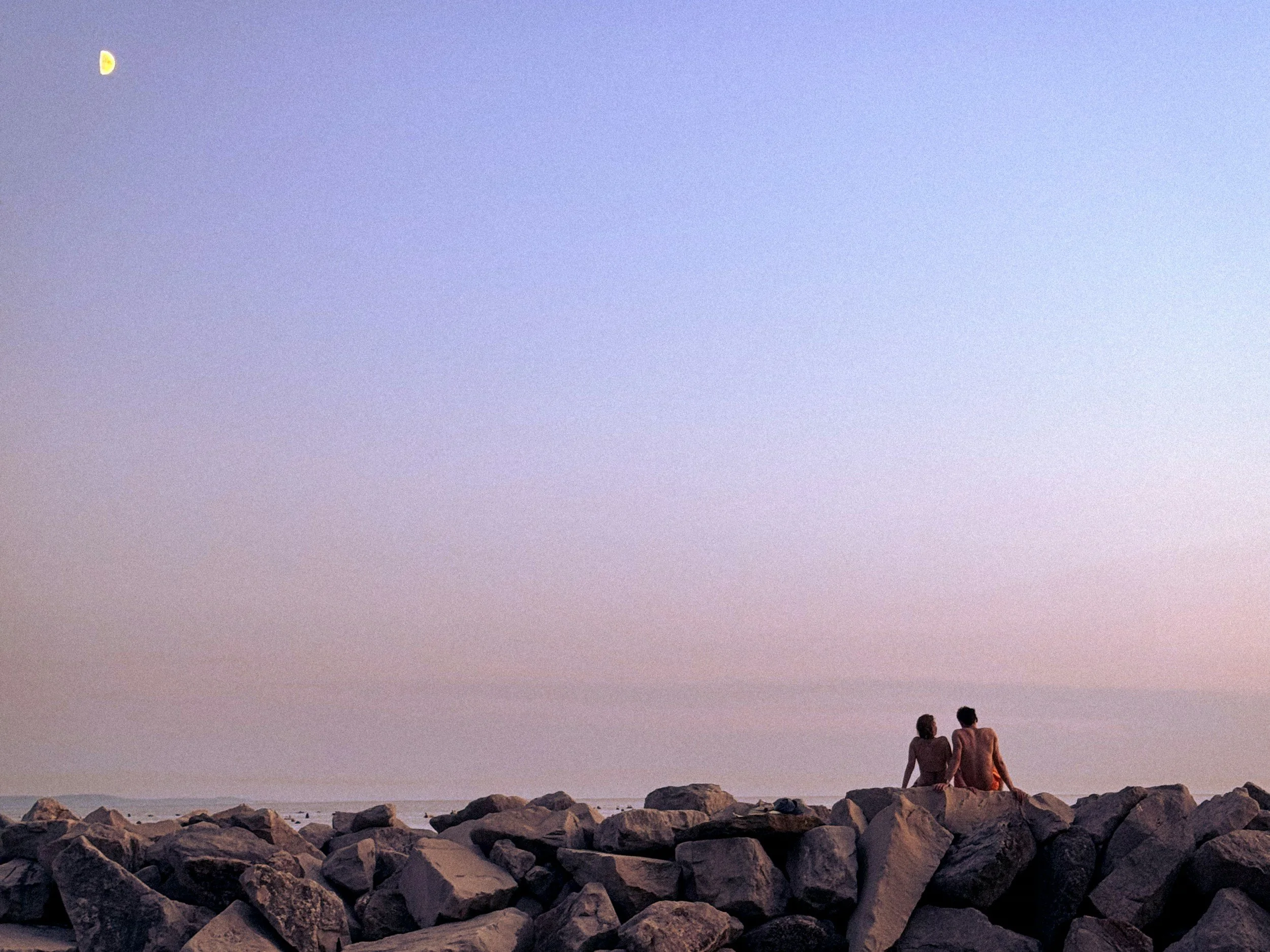 couple sitting on rocks overlooking the ocean