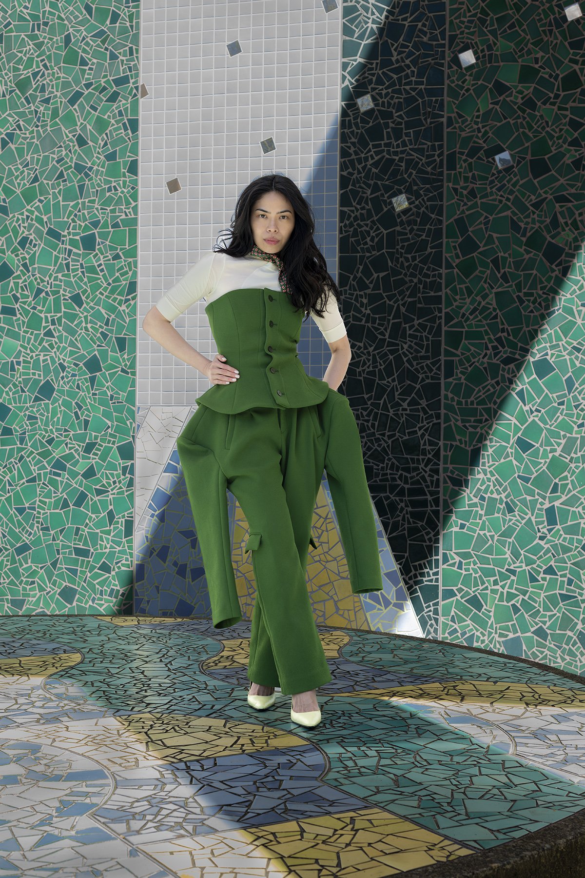 Woman wearing green Issey Miyake suit photographed against tiled background in Seattle New York and Los Angeles in natural light