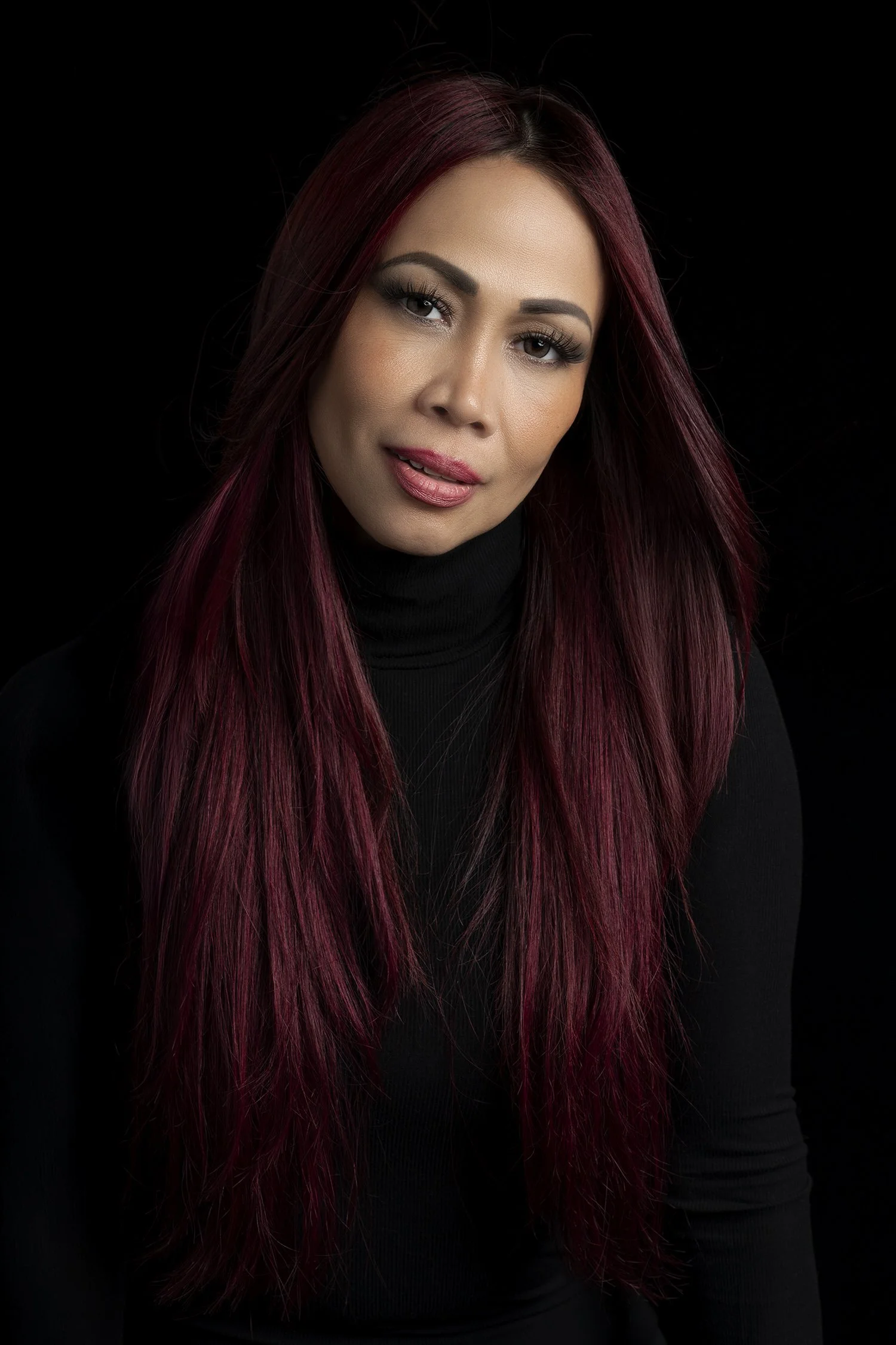 Woman with cherry red hair photographed against black back drop in Seattle New York and Los Angeles