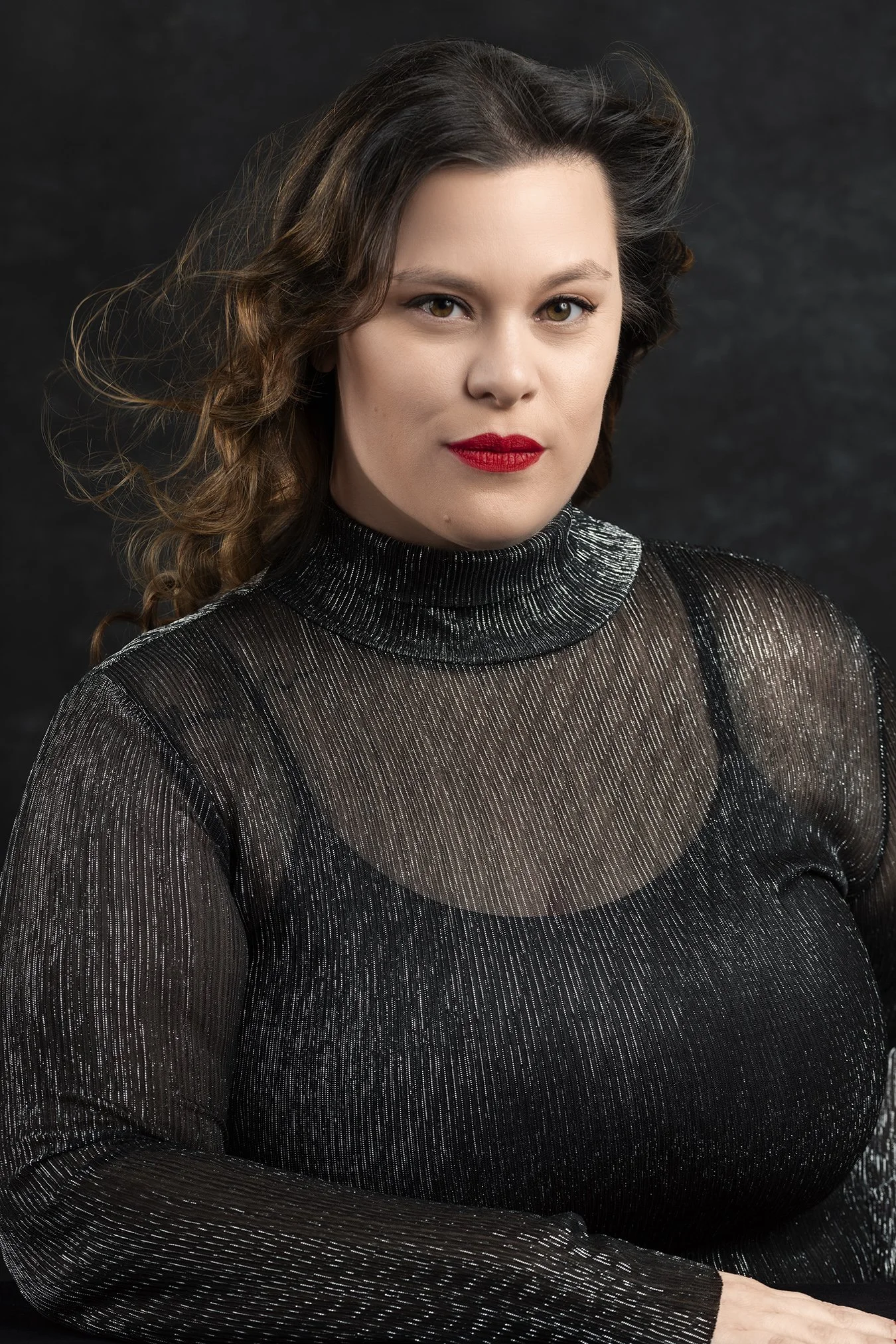 Woman with flowing hair wearing bright red lipstick in sparkly black blouse photographed in Seattle New York and Los Angeles