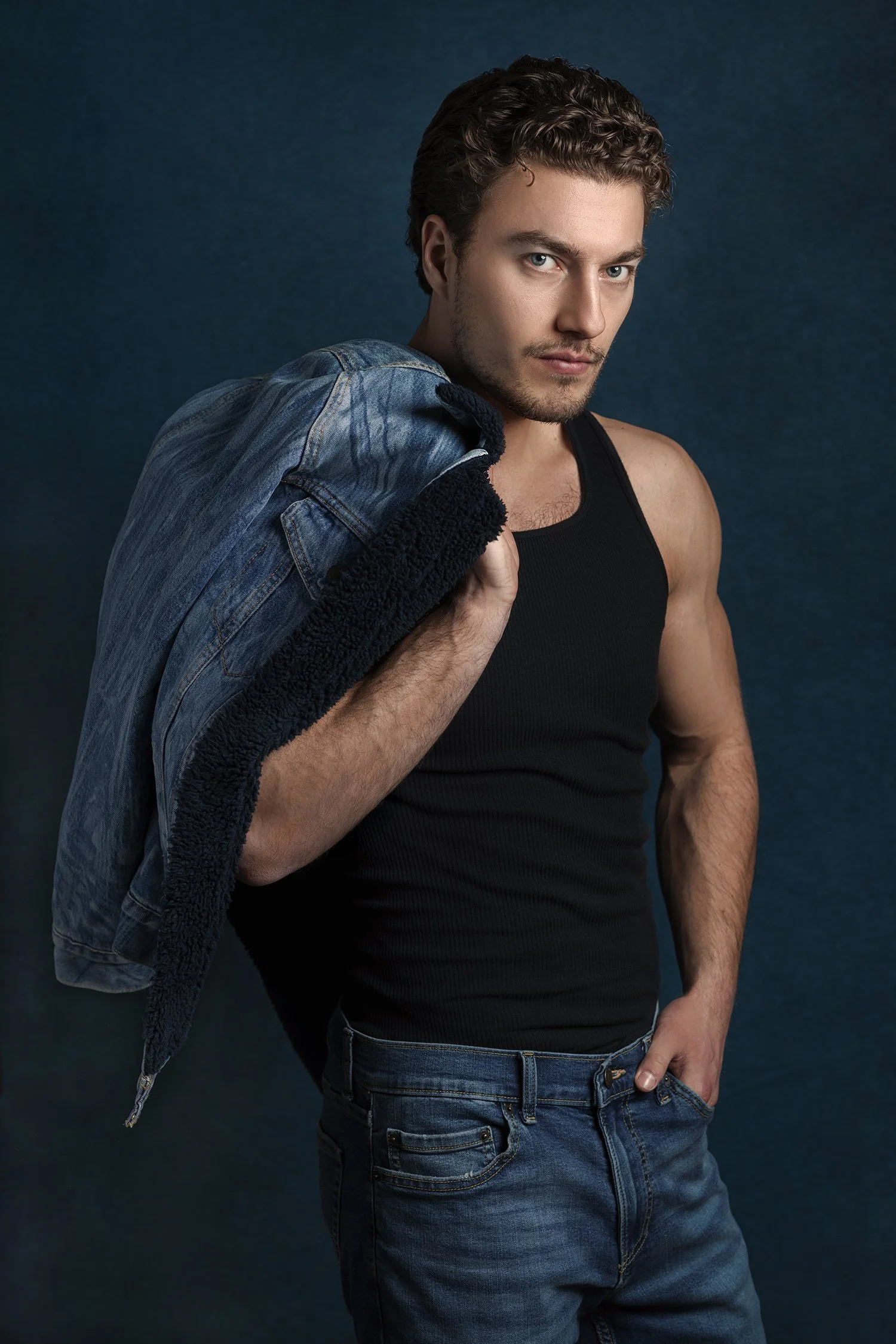 Male model with muscles and black tank top in denim photographed in studio in Seattle New York and Los Angeles
