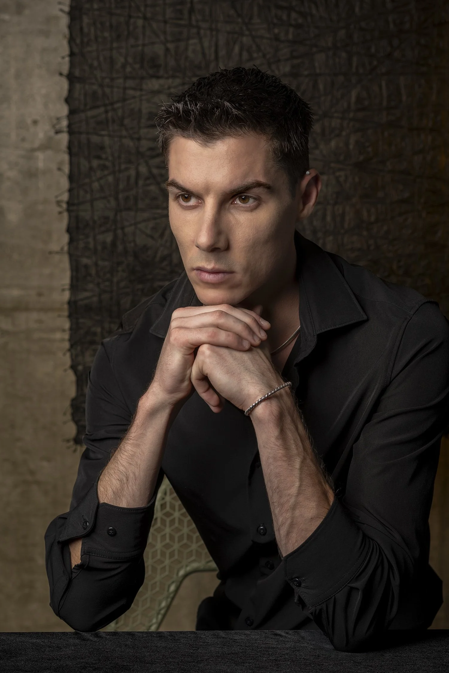 Russian model man wearing black cotton button up shirt photographed in studio against black textured paper and concrete wall in Los Angeles New York Seattle