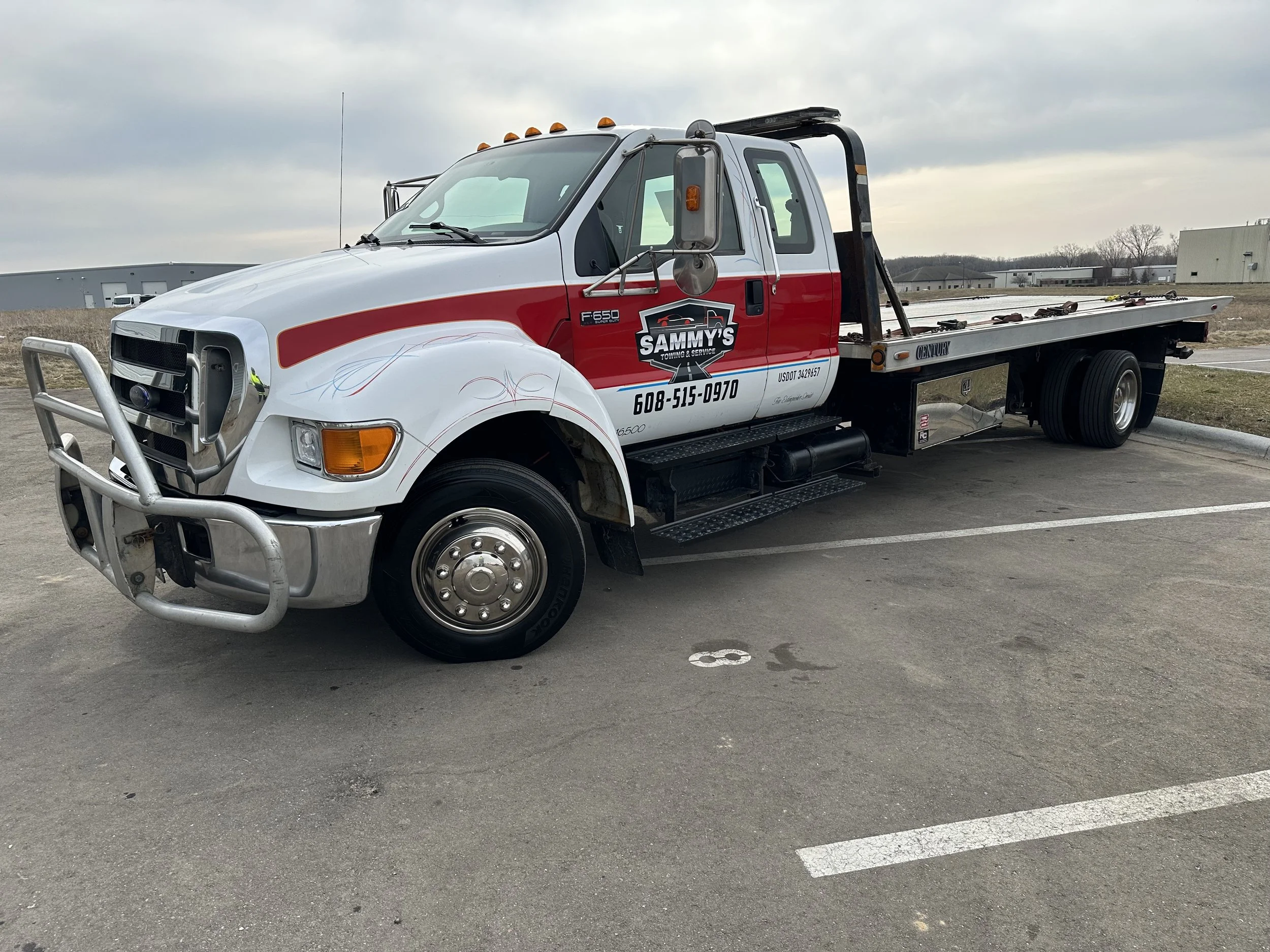 A tow truck parked in a lot with numbered parking space 8 marked on the ground.