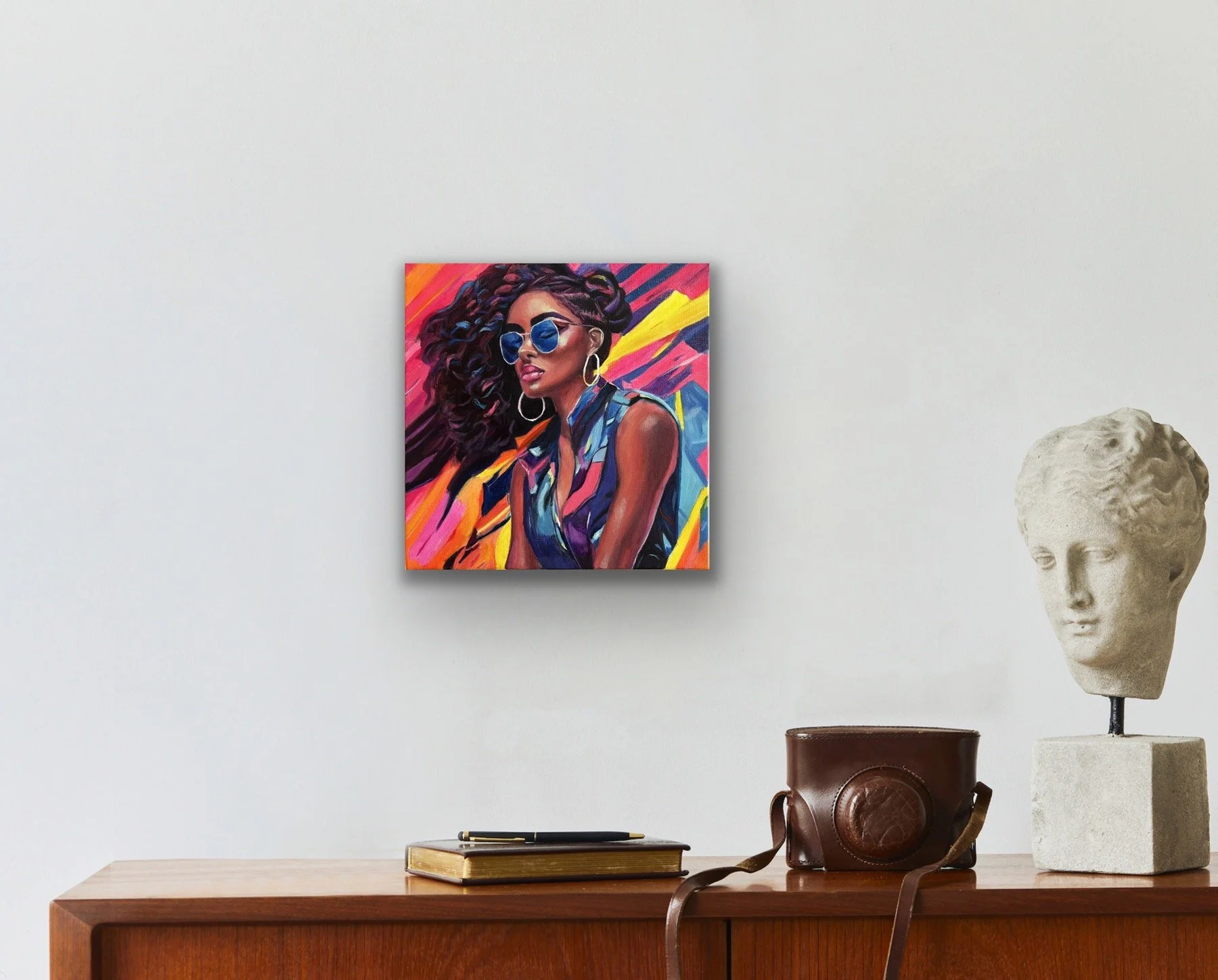 A bold acrylic portrait of a woman wearing blue sunglasses and hoop earrings, styled in a modern interior with a wooden console, classical bust, and vintage accessories.