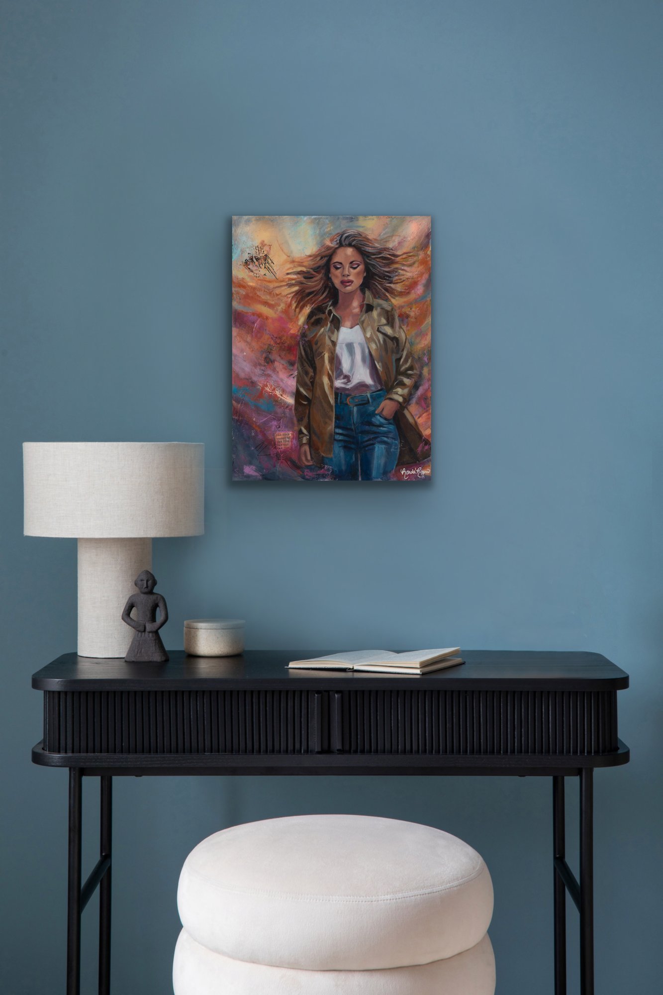 Embrace the Storm painting on a blue-teal wall above a black console table with a table lamp and decorative objects