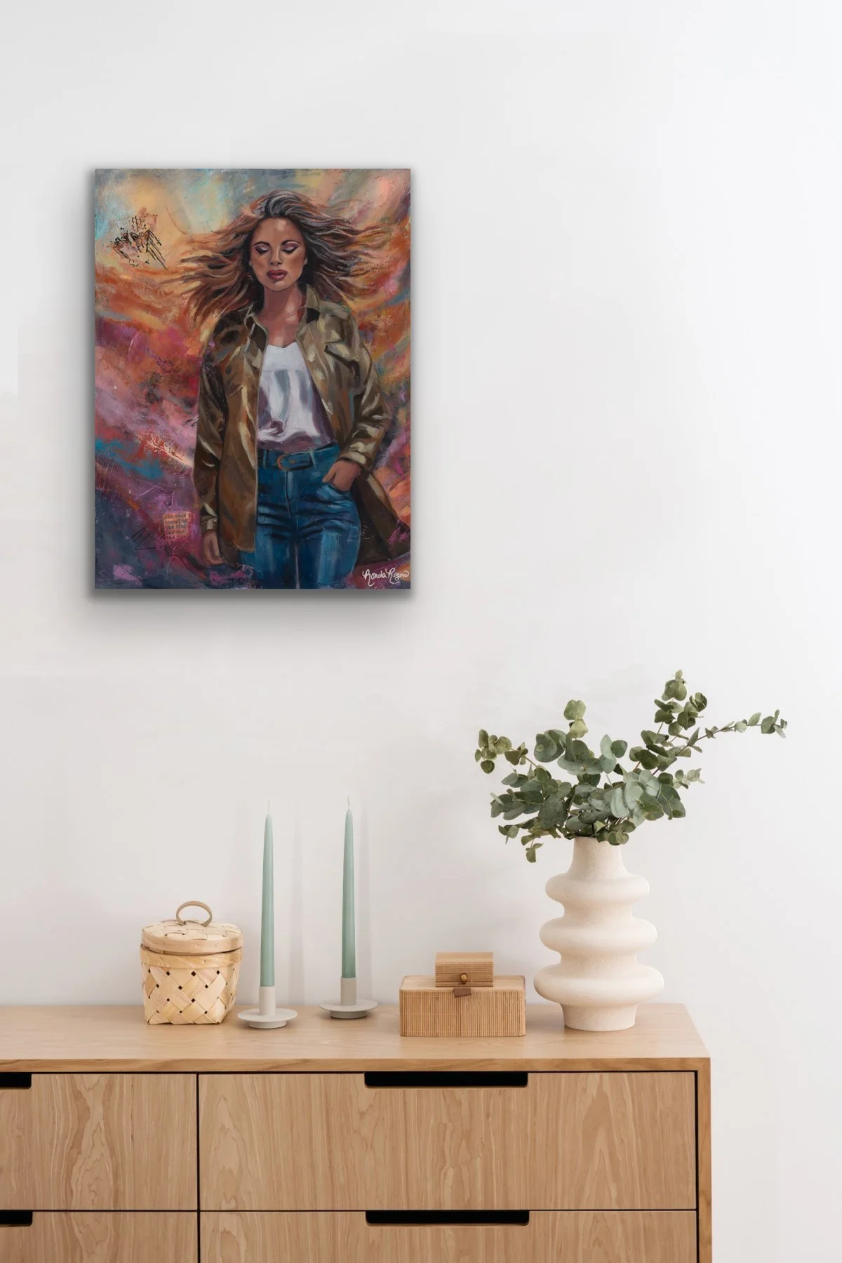 Embrace the Storm painting above a light wood dresser styled with taper candles and a eucalyptus arrangement