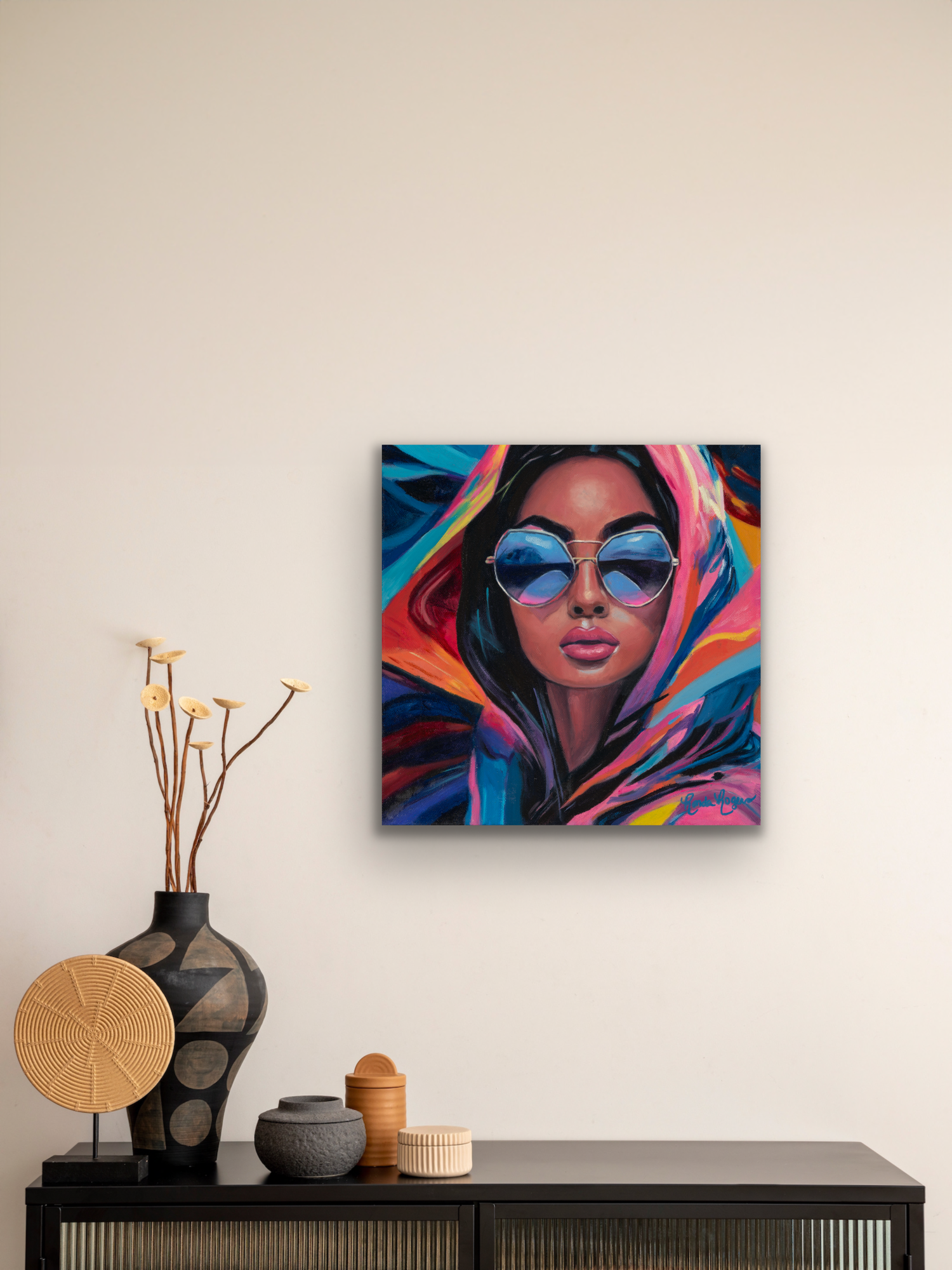 Vibrant Vision painting on a cream wall above a black console table with a woven wall basket, ceramic vases, and dried flowers