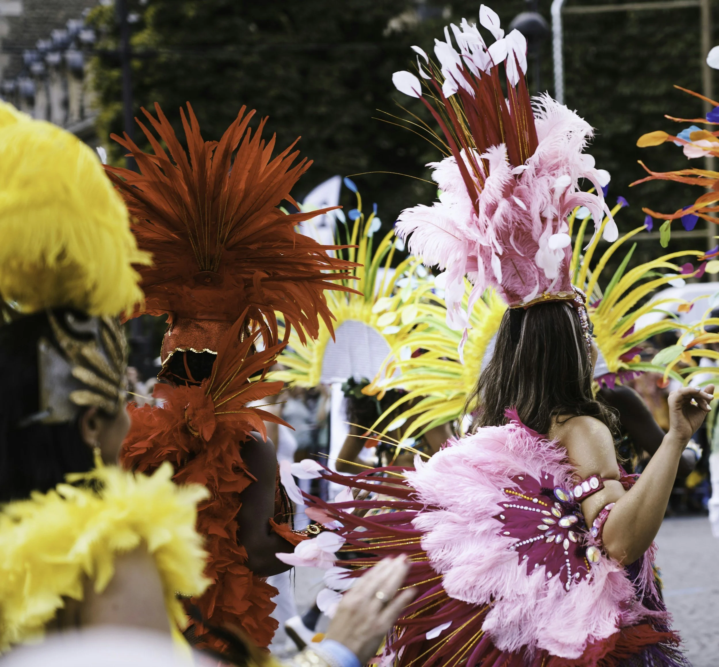 People in colorful feathered costumes participating in a parade or festival.