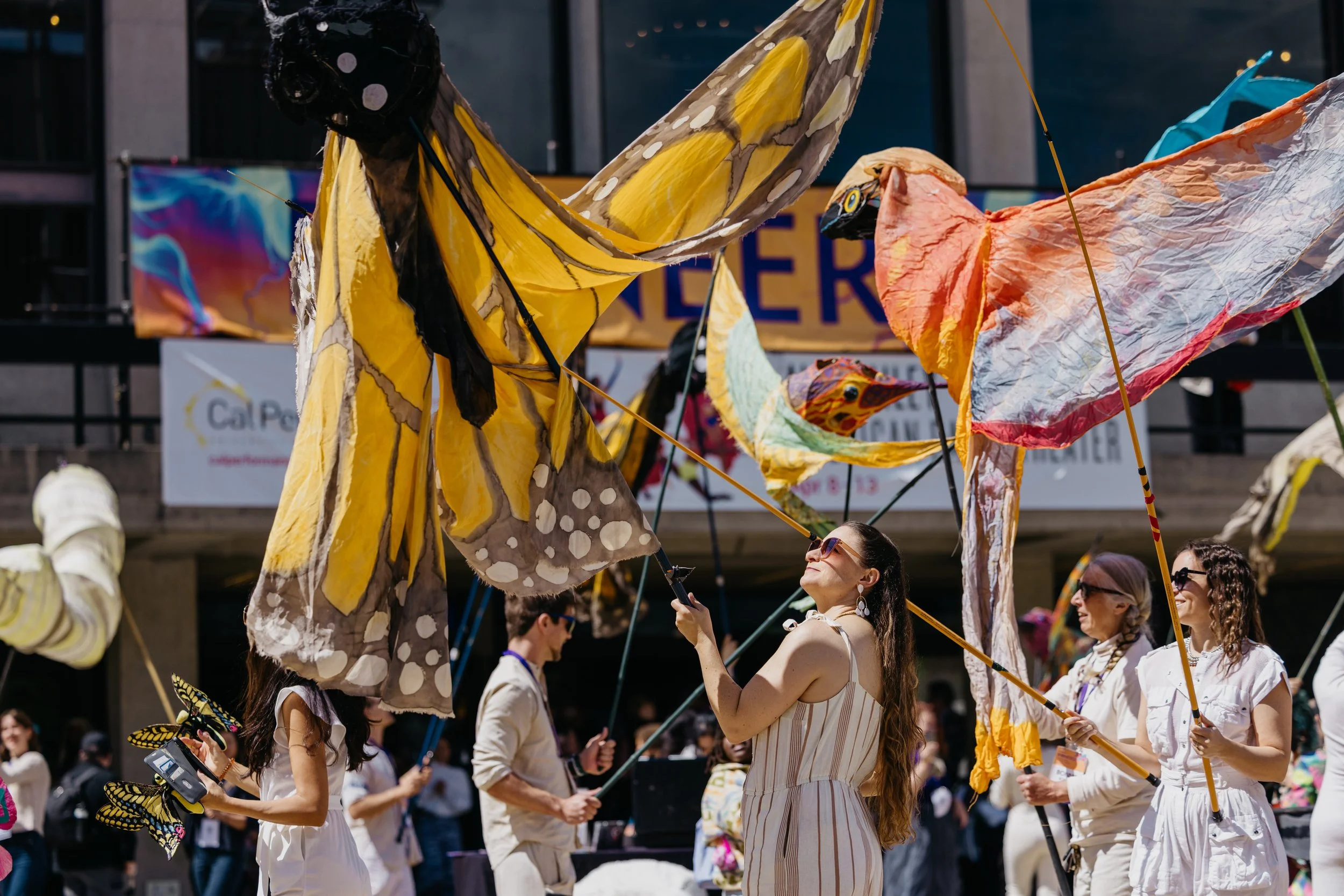 People at an outdoor event flying large, colorful butterfly-shaped kites.