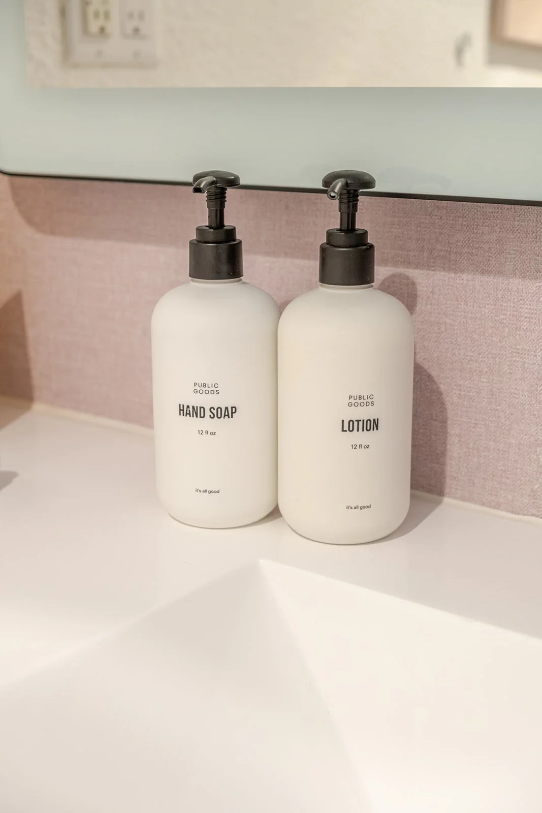 Two white bottles labeled 'Hand Soap' and 'Lotion' with black pump dispensers on a bathroom counter.
