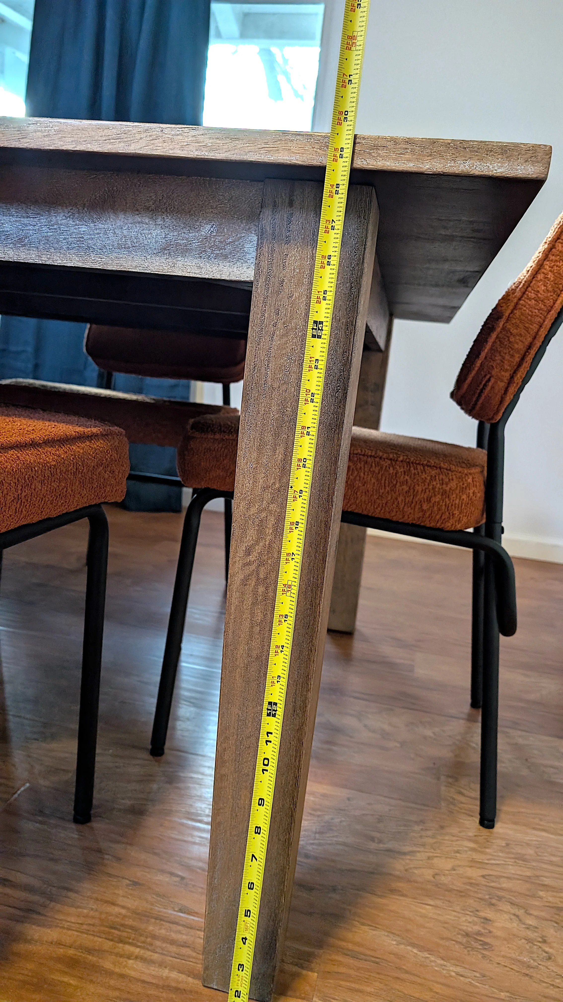 A wooden table with a tape measure showing height from the floor to the top of the table.