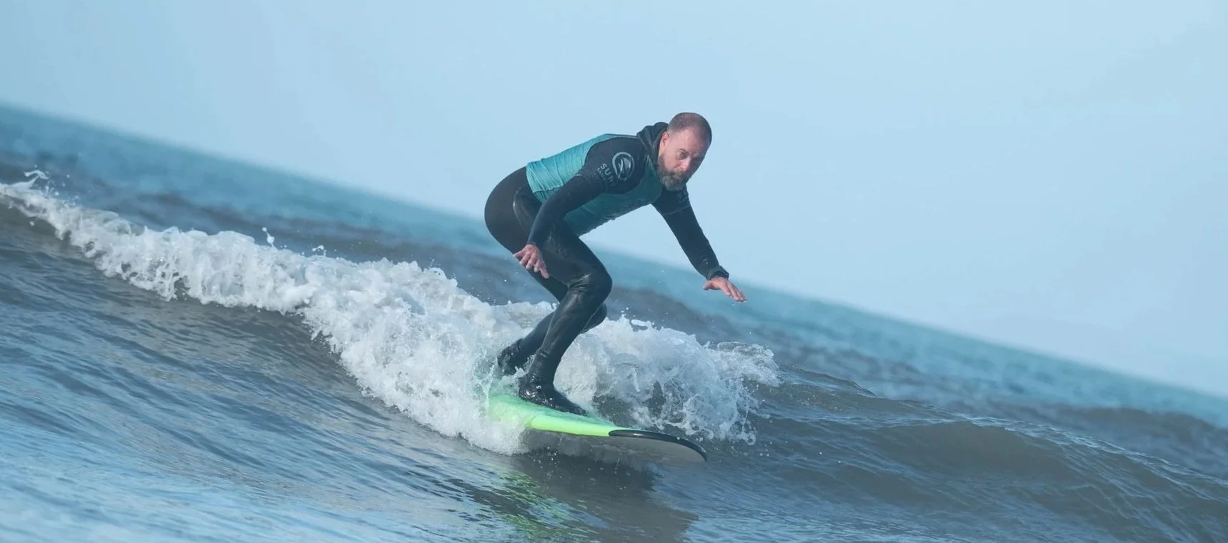 Man surfing on a small wave in the ocean.