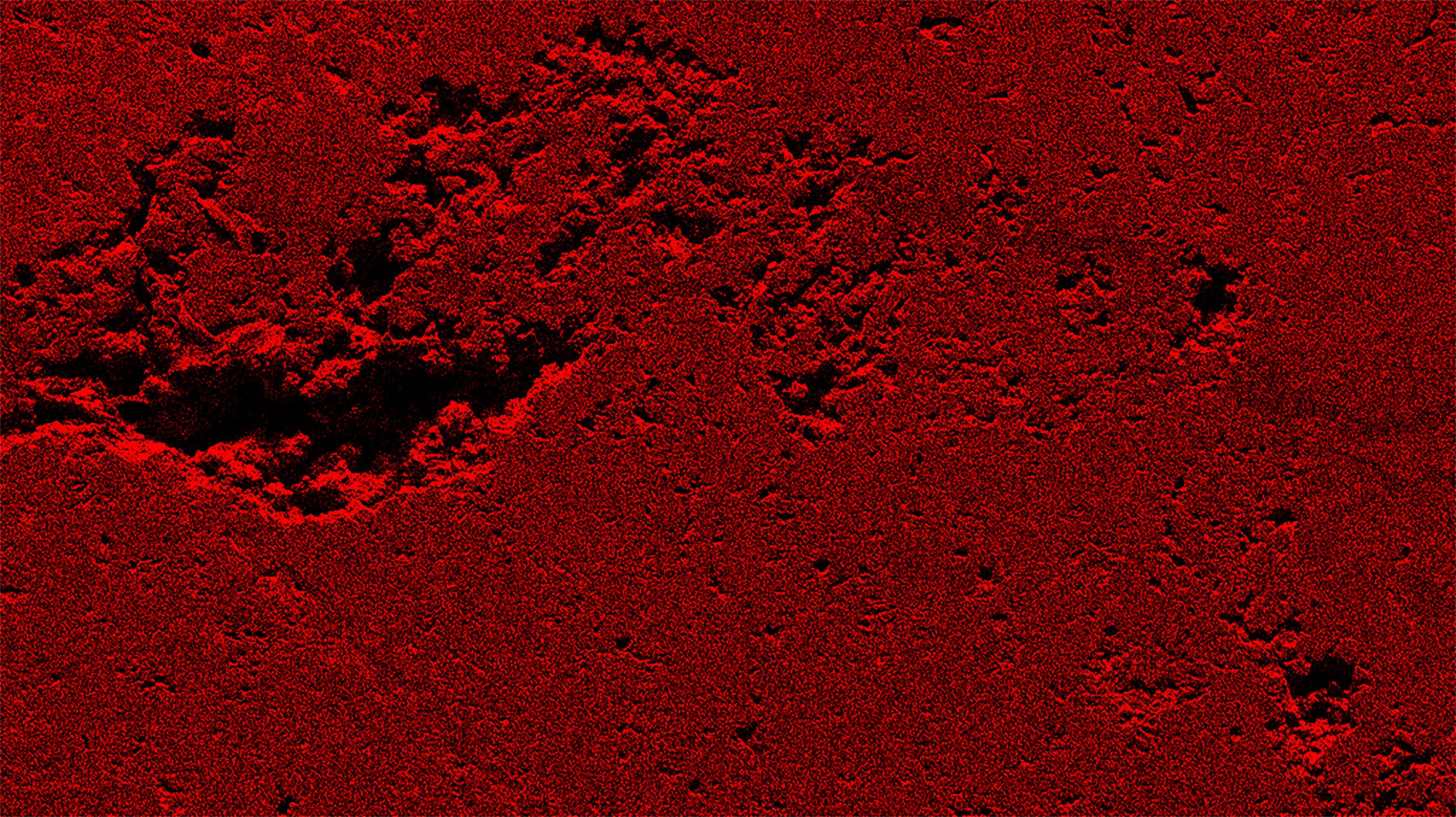 Red textured surface with dark patches resembling a granular or rocky terrain.