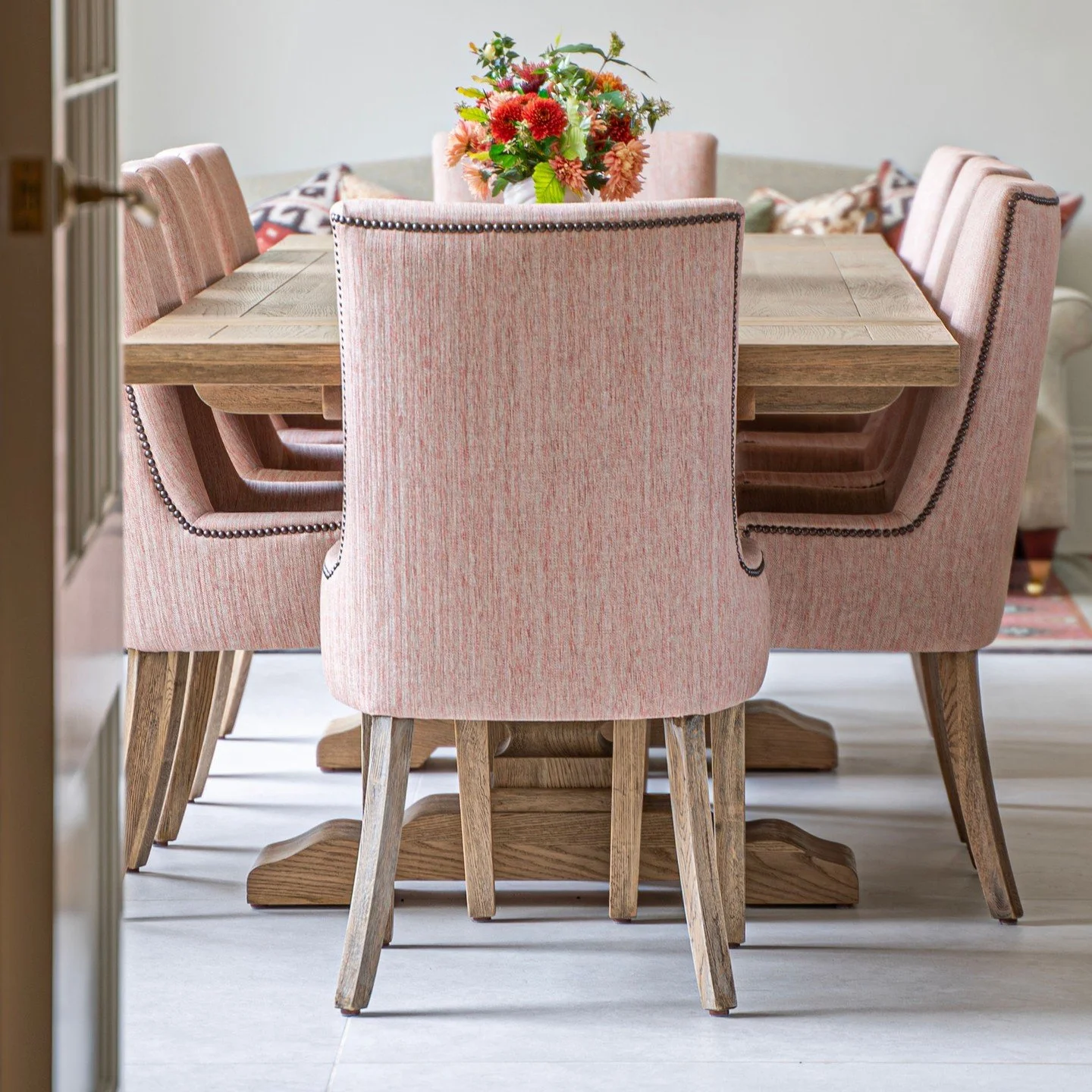 A quiet moment at the dining table where comfort and craftsmanship do the talking.

These bespoke oak chairs, upholstered in a textured blush Jane Churchill weave, were designed with a soft curved back and finished with hand applied stud detailing. T