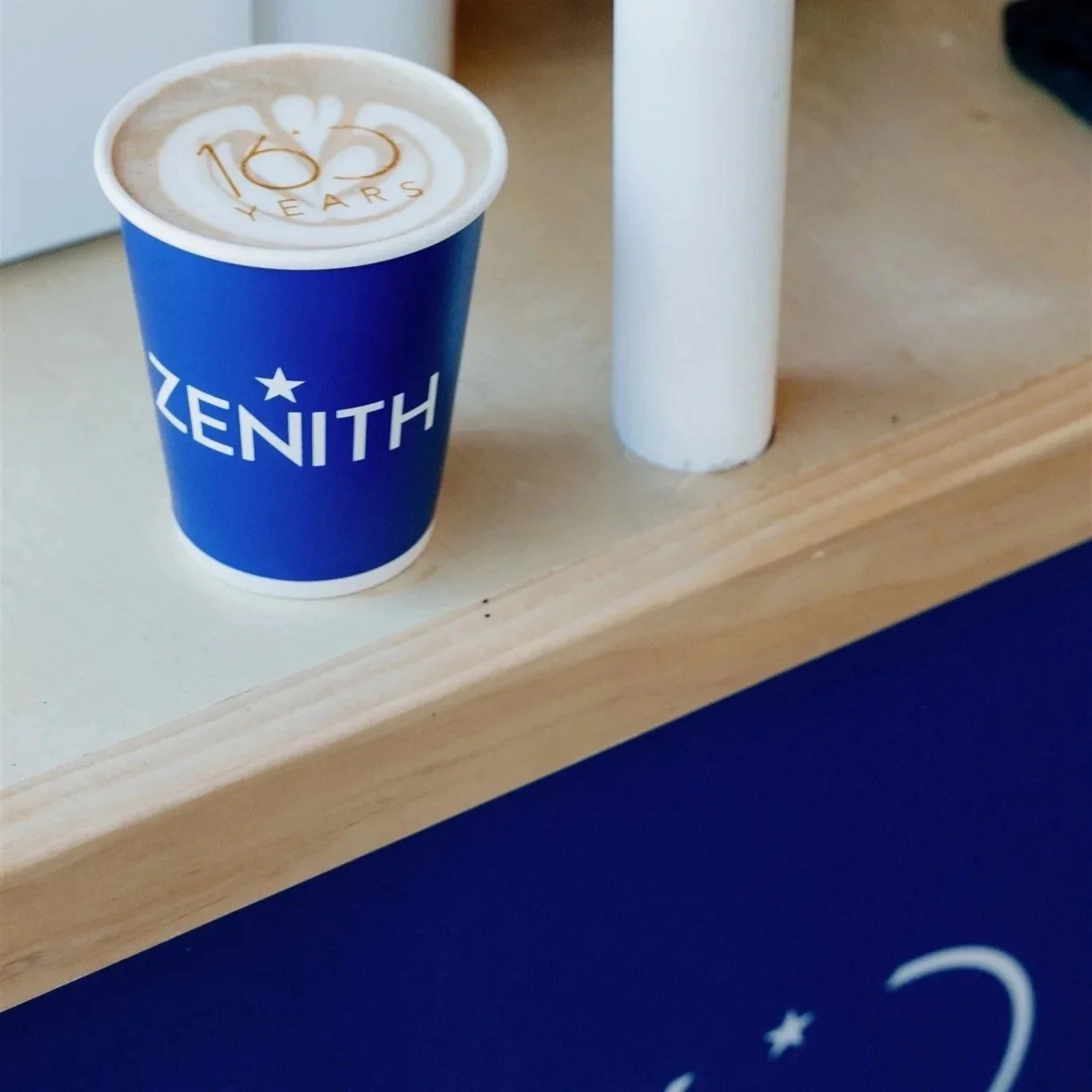 Blue coffee cup with 'ZENITH' logo, containing a latte with foam art and '185 YEARS' printed on top of the foam custom coffee cart catering