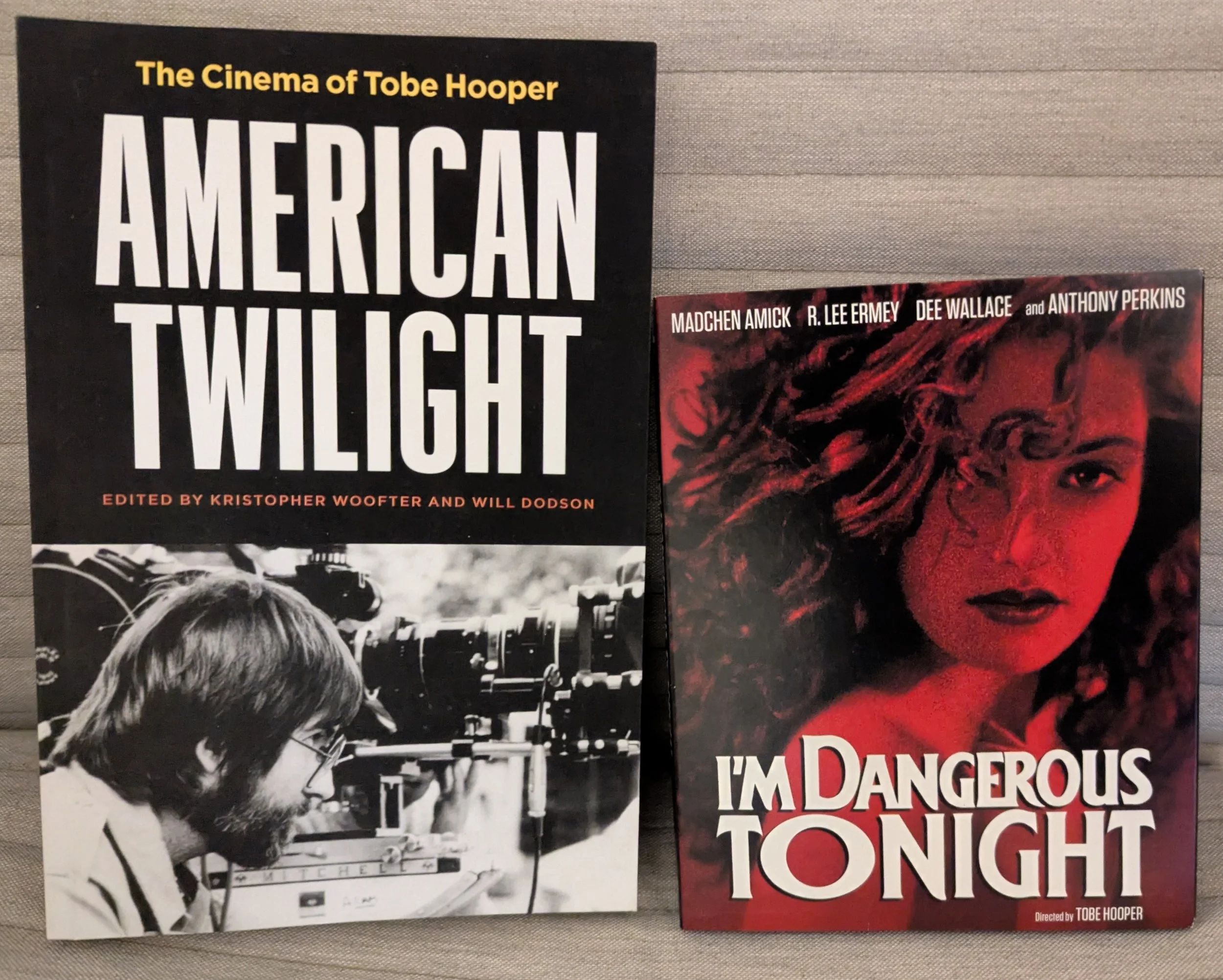 On left is book American Twilight. Title on top half in white font on black, black and white picture of young Tobe Hooper looking into camera. On right is case for I'm Dangerous Tonight. Headshot of Madchen Amick all in red with movie title in white.