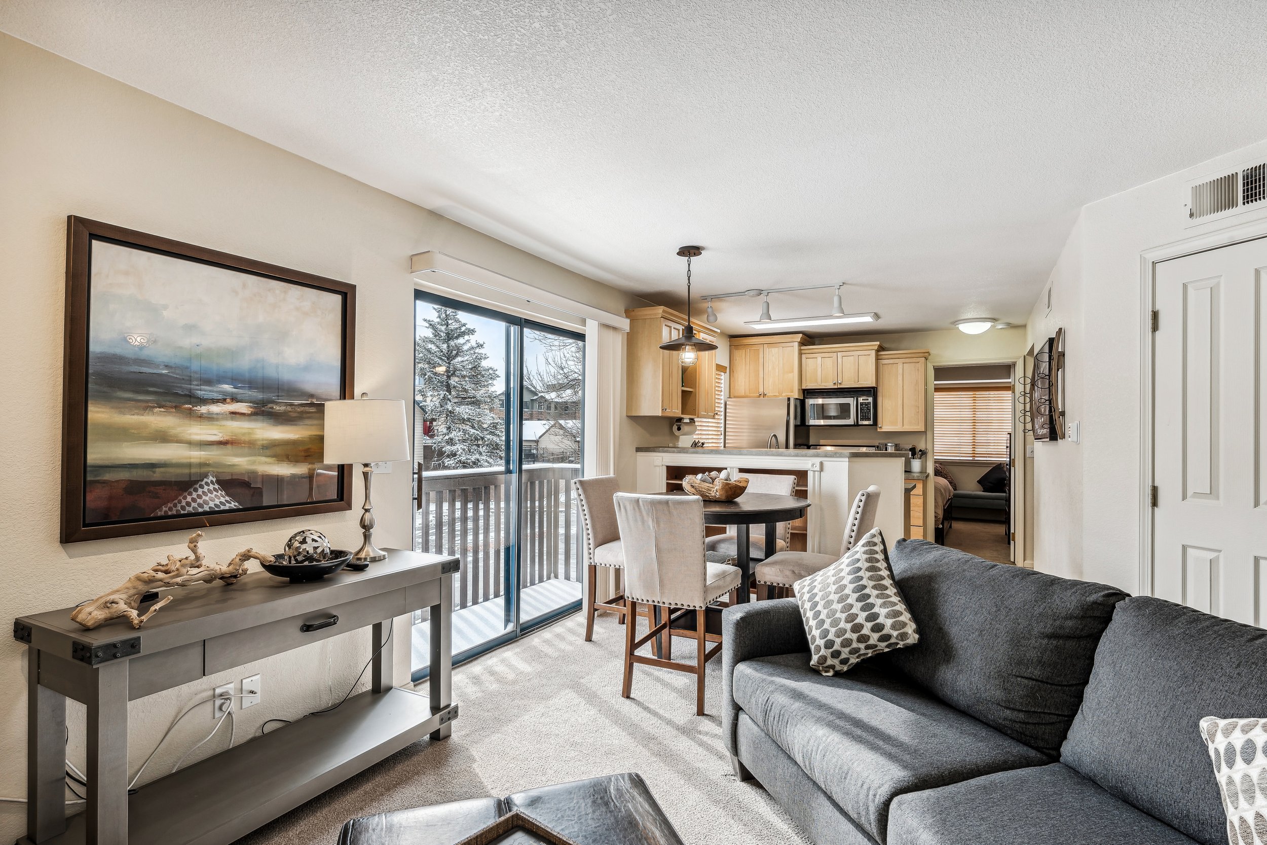 Unit 207 - A photograph of the living room. Dining area, patio, and kitchen featured.