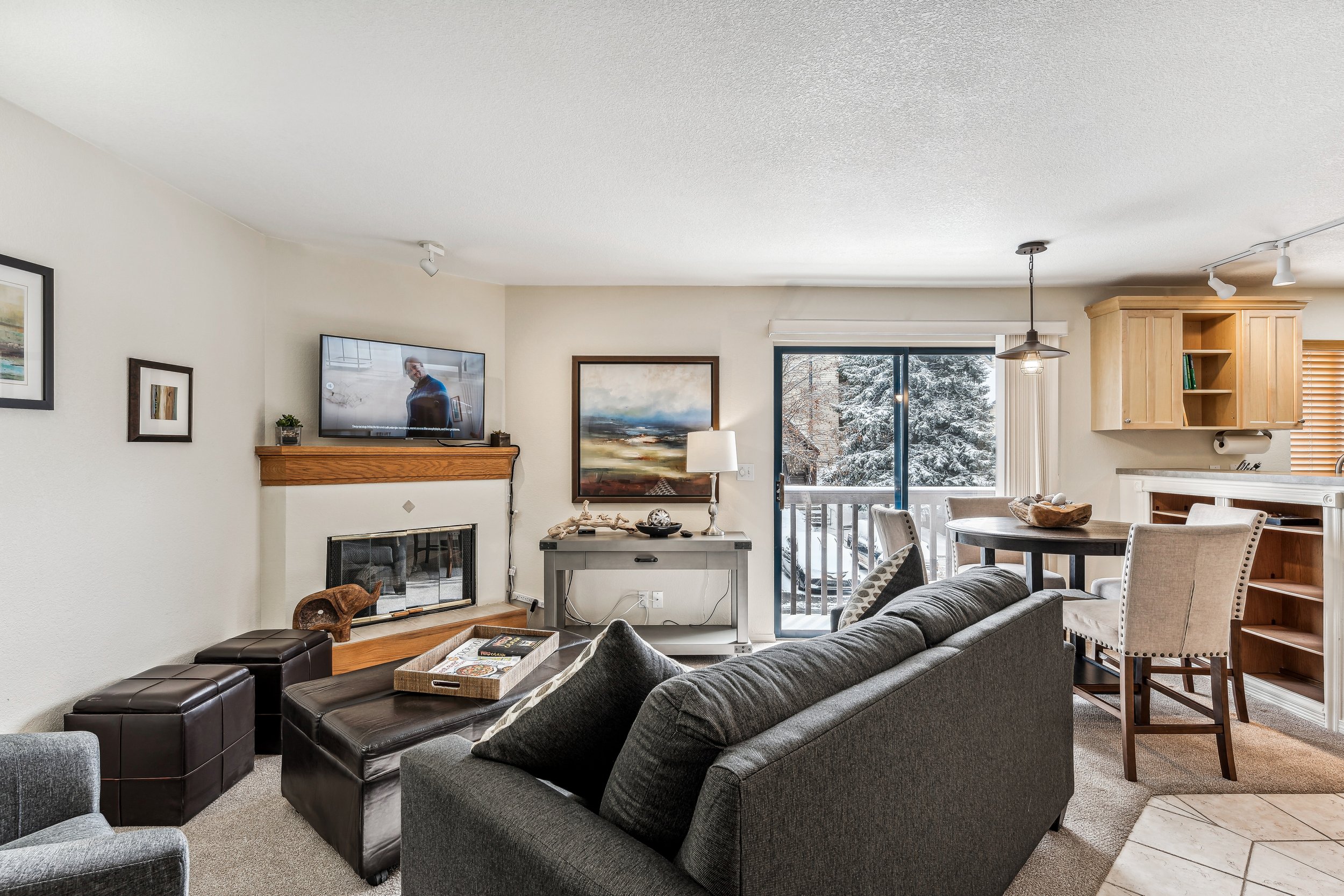 Unit 207 - A photograph of the living room. Dining area, patio, flatscreen television and gas fireplace featured. Angle 2