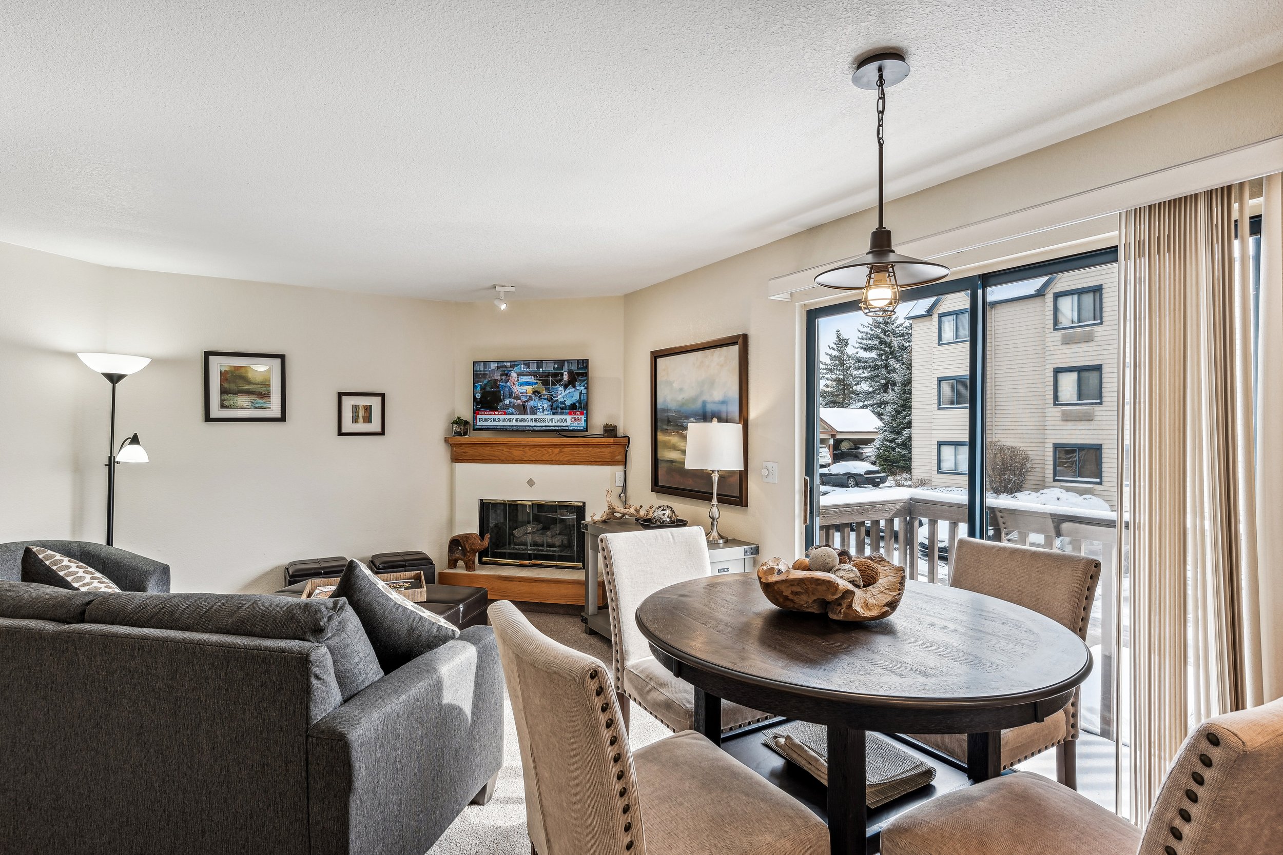 Unit 207 - A photograph of the living room. Dining area, patio, flatscreen television and gas fireplace featured.