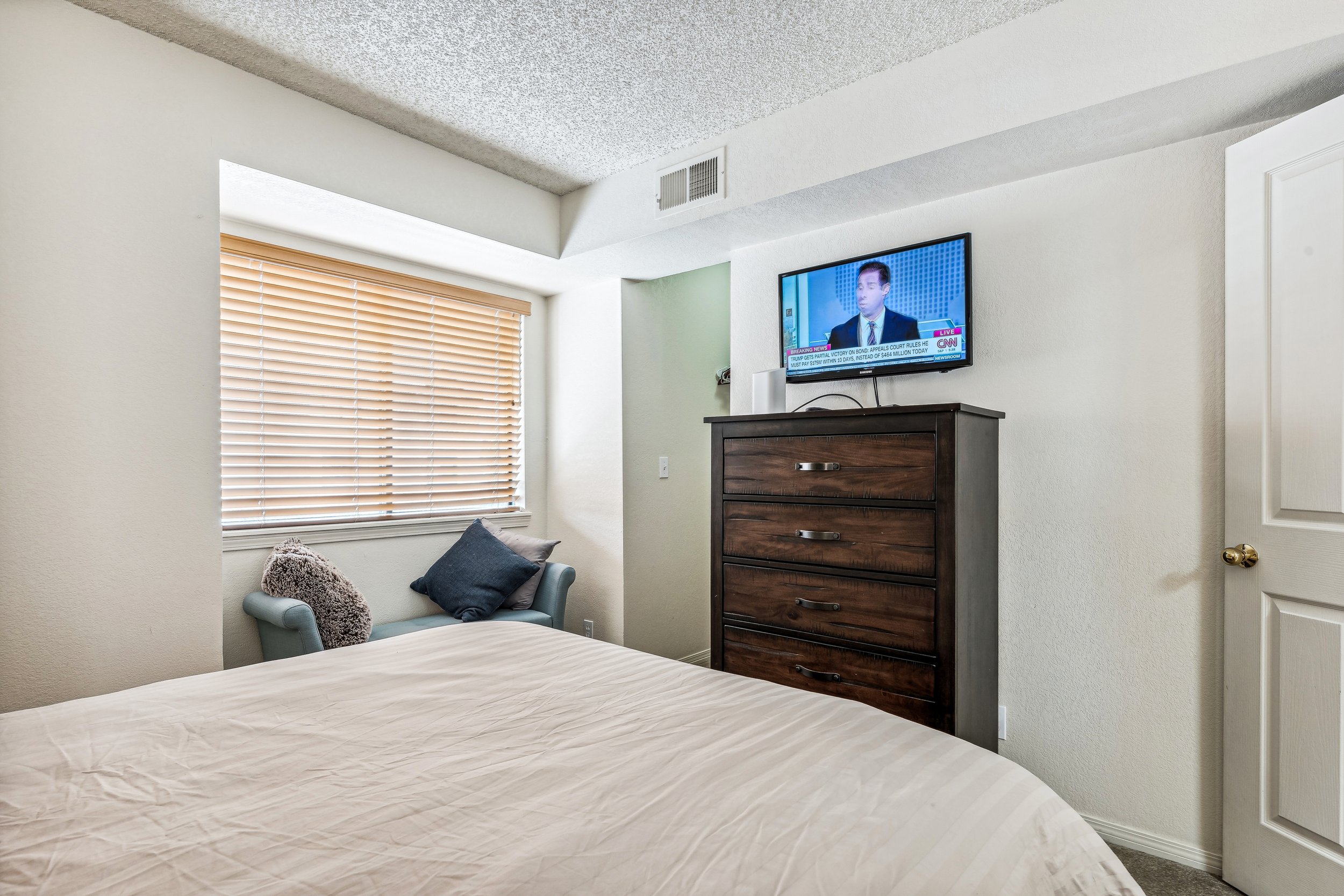 Unit 207 - A photograph of the smaller bedroom. Flatscreen and dresser featured.