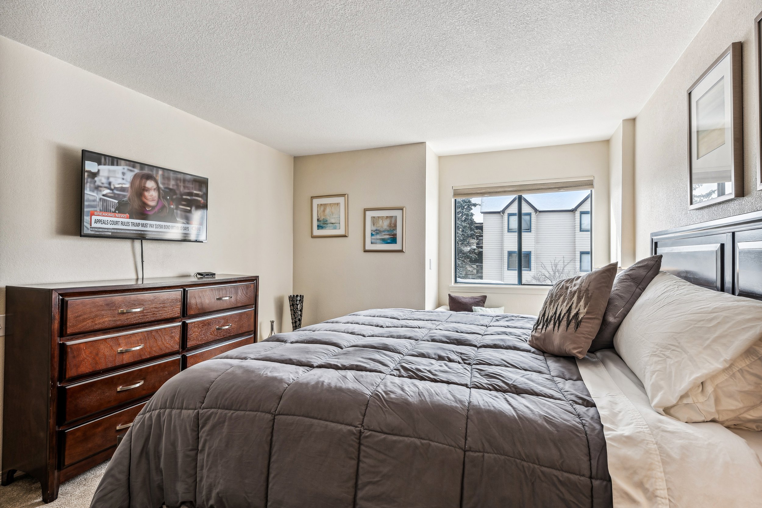 Unit 207 - A photograph of the large bedroom. Flatscreen and dresser featured.