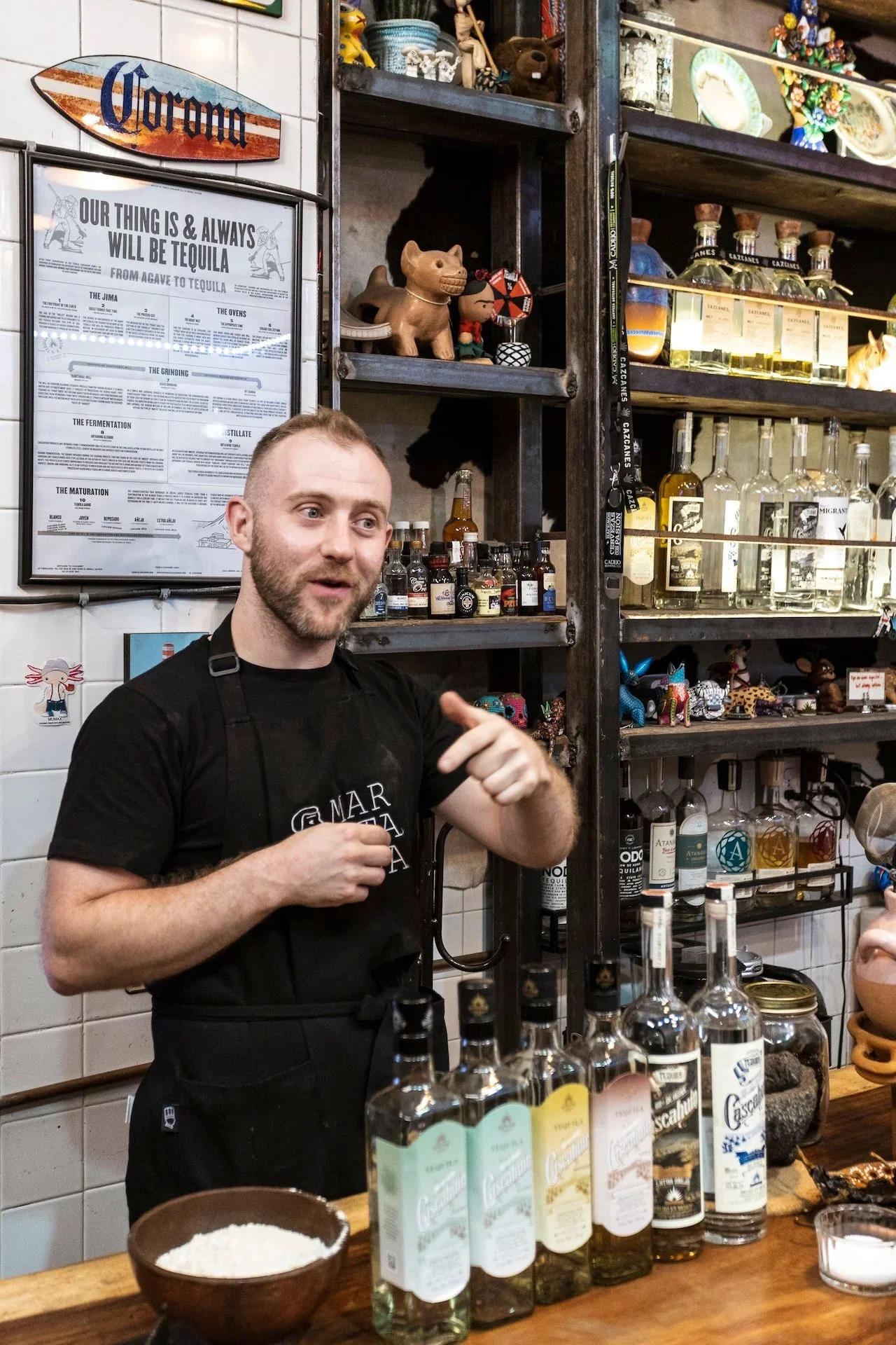 A Martaja chef talks about the history of tequila, how tequila is made and how tequila is different to mezcal in a colorful vintage tequila tasting room as part of a cooking class.