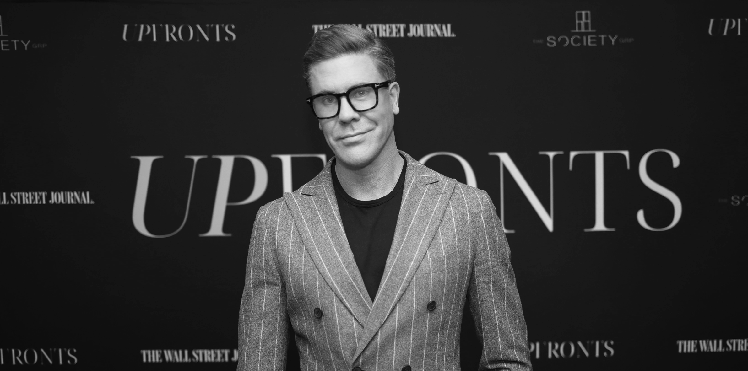 Black and white portrait of a woman smiling with long hair and wearing earrings.