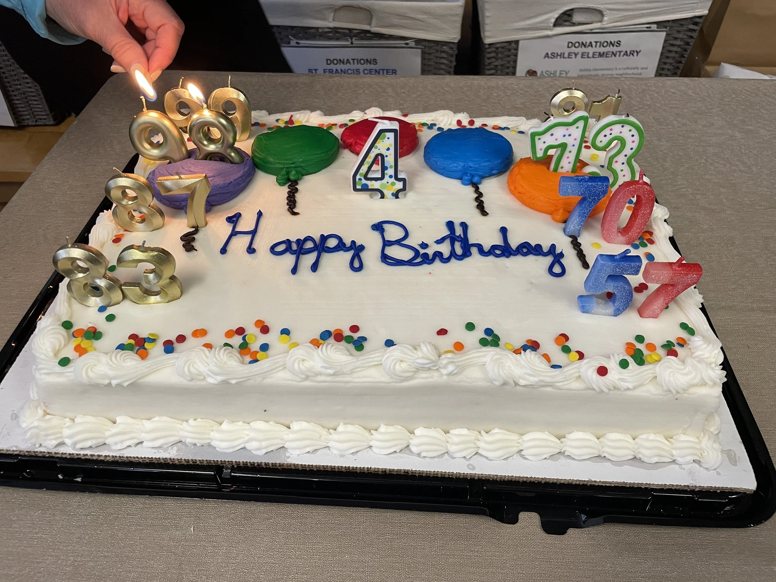 A joint birthday cake with plenty of different age candles on it- from 4 to 99