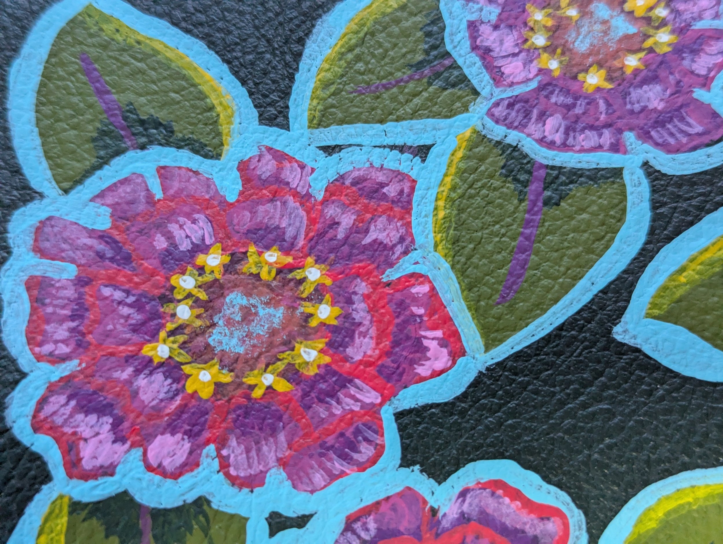 painted leather cover showing a colourful zinnia flower with a turquoise outline
