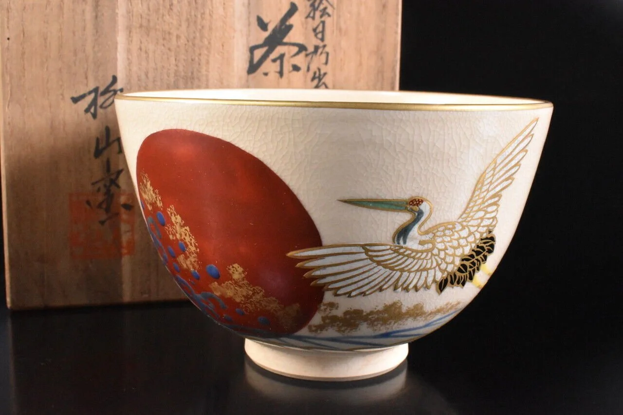 Decorative ceramic bowl with a painted design of a heron and a large red circle, set against a neutral background.