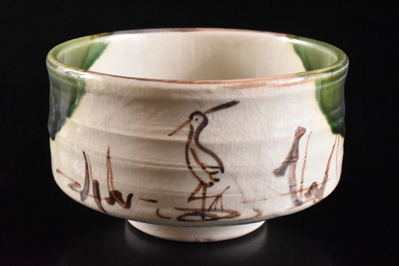 A ceramic bowl with hand-painted depictions of a bird and abstract brushstrokes, featuring a crackled glaze finish and green accents around the rim.