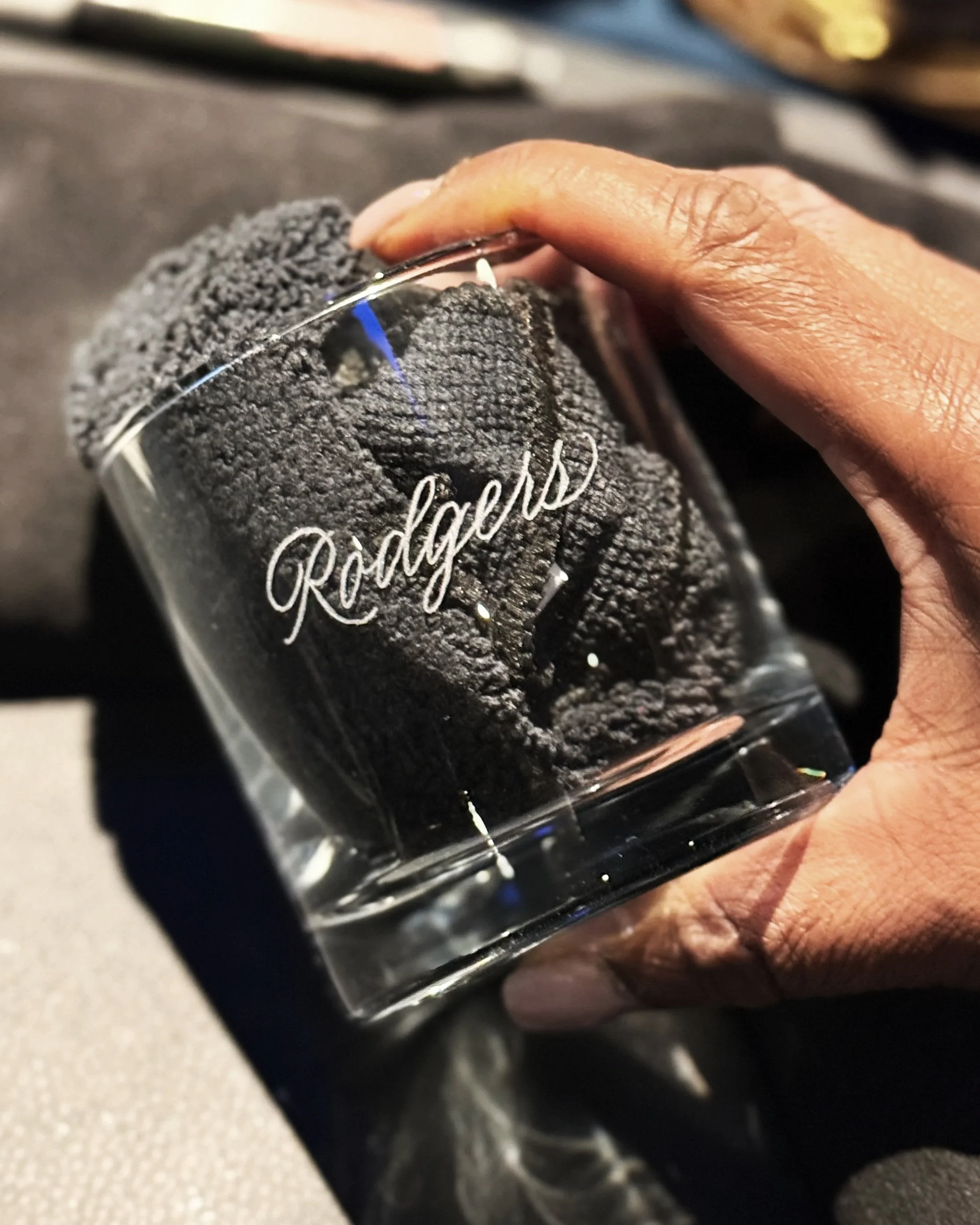 artist holding a hand-engraved whiskey glass completed at a gala event