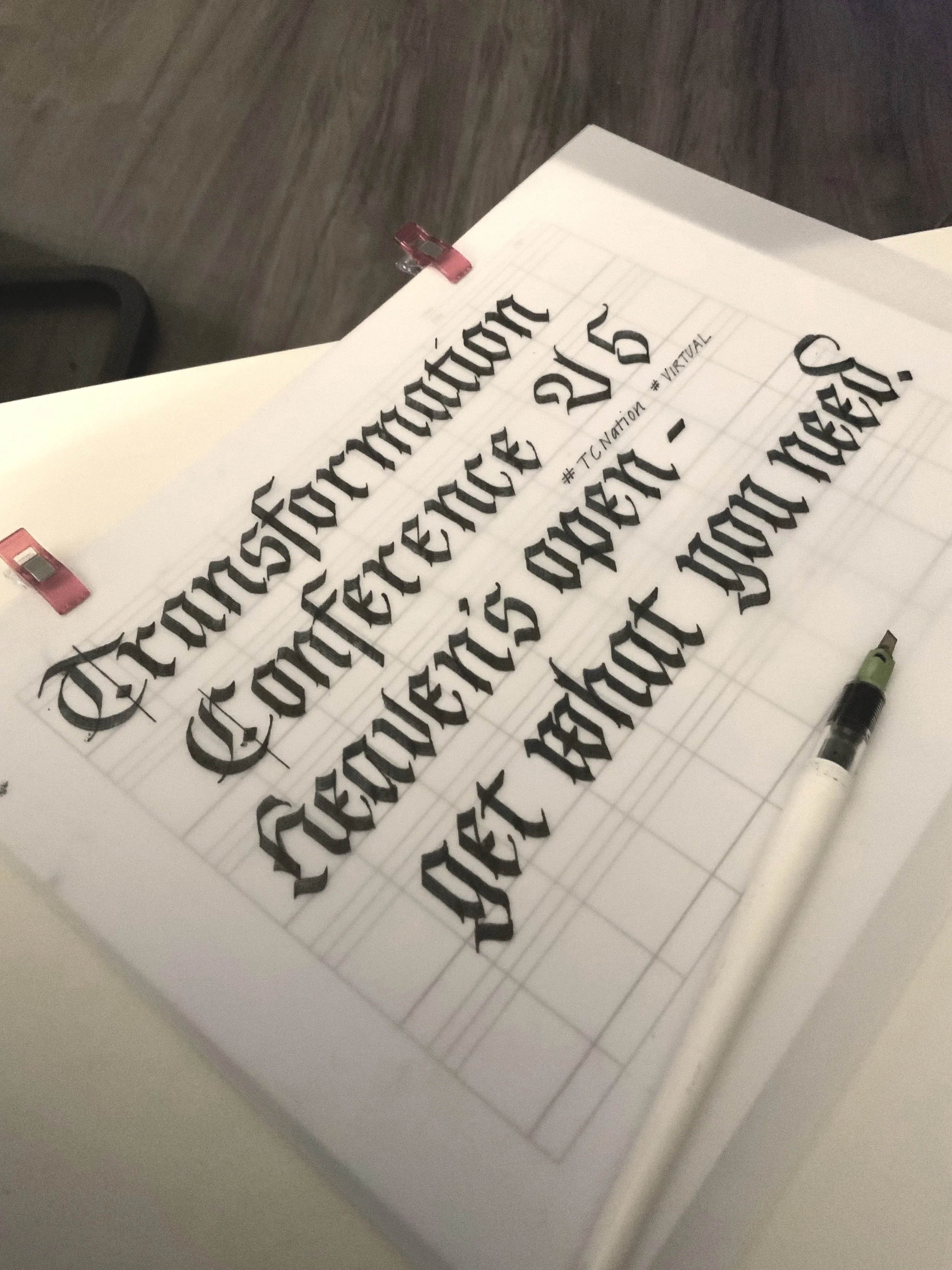 blackletter in black ink on tracing paper atop a guide sheet with a pilot parallel pen
