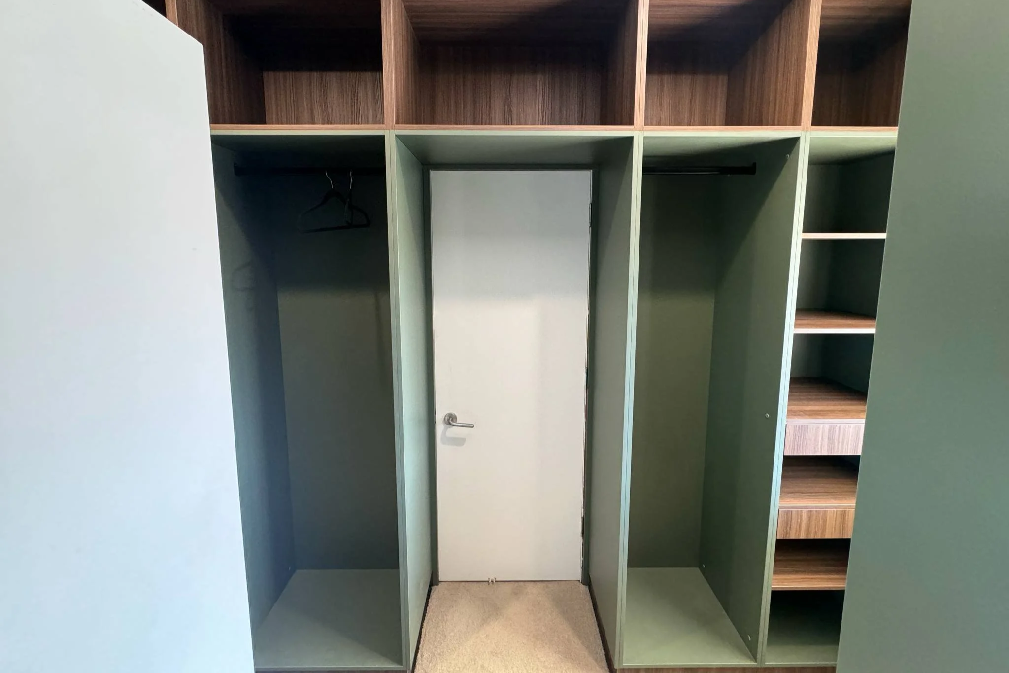 Empty built-in closet with open compartments, a few hangers, and shelves.