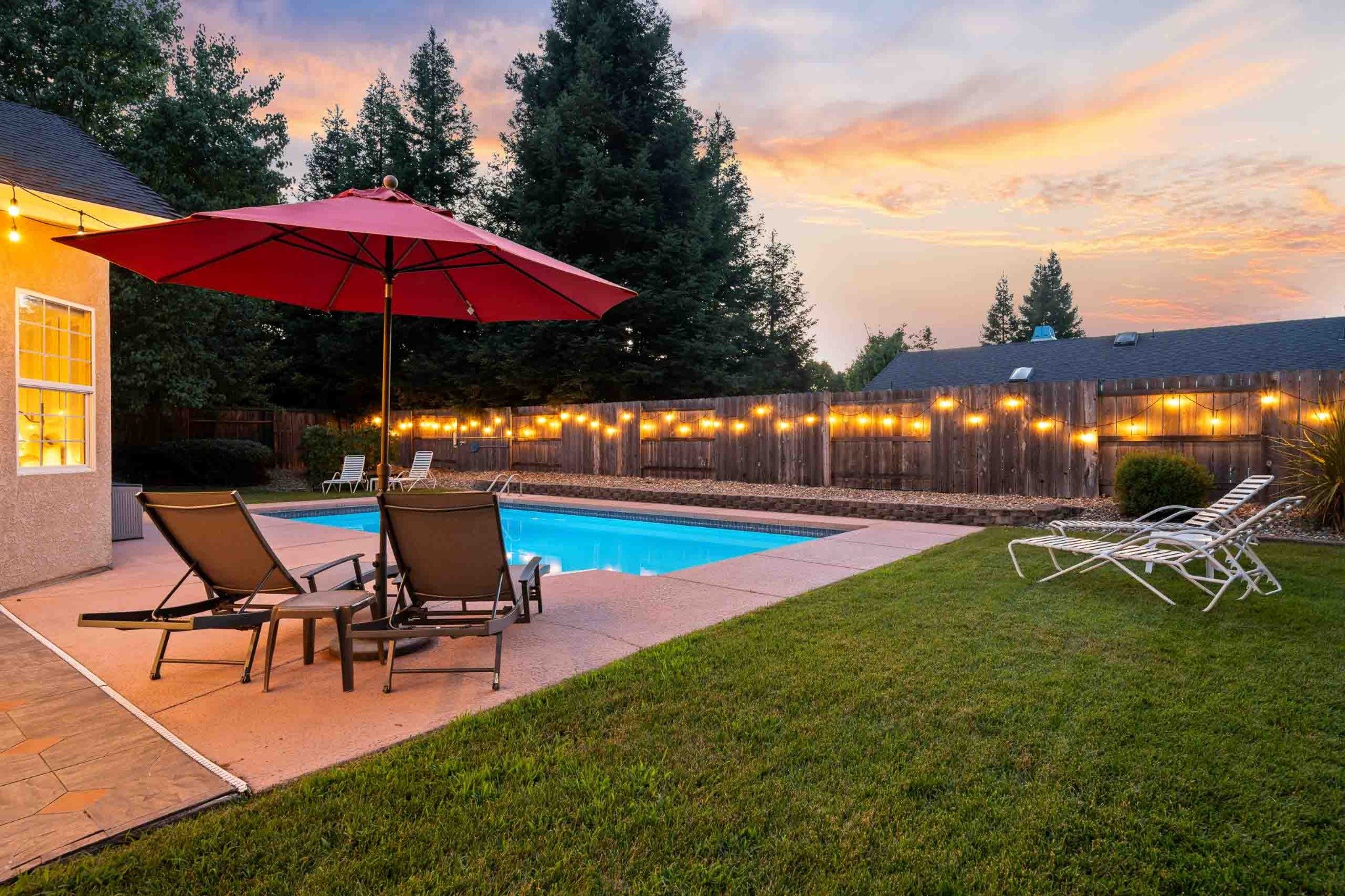 Backyard swimming pool with lounge seating and a colorful sunset in Redding, California.
