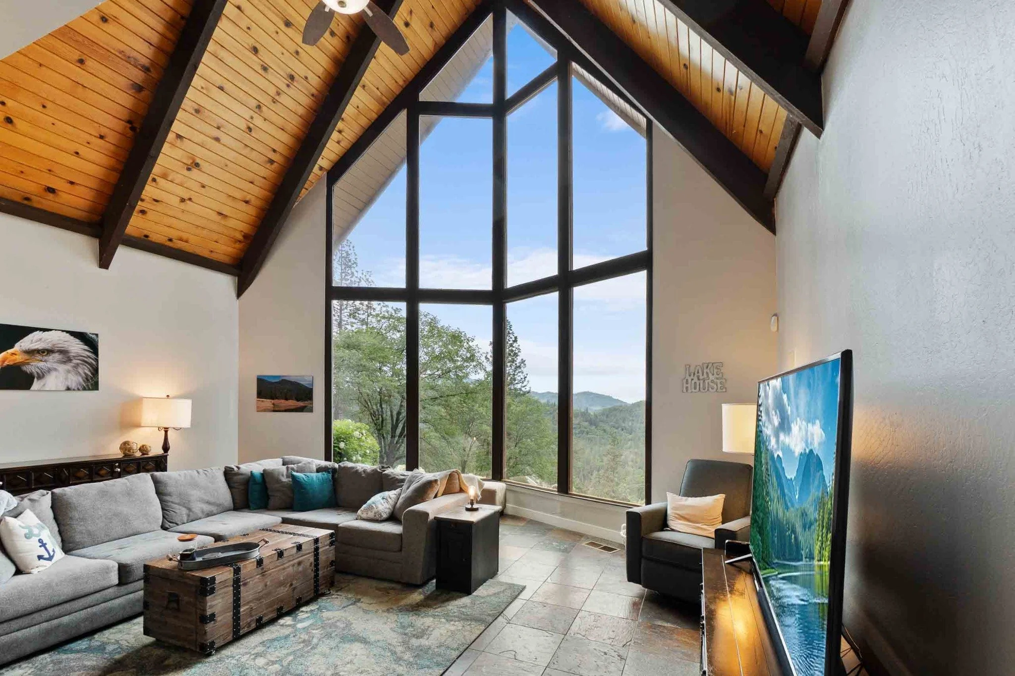 Luxury living room with a vaulted wood ceiling, floor-to-ceiling windows, and mountain views near Redding, California.