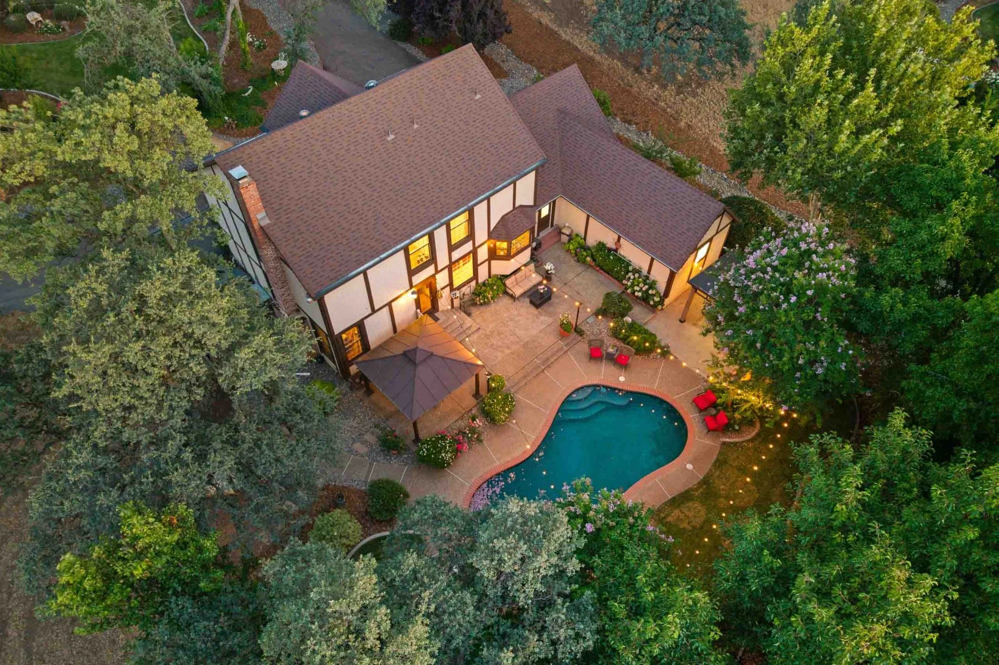 Aerial view of a luxury home with a backyard pool and mature trees in Redding, California.