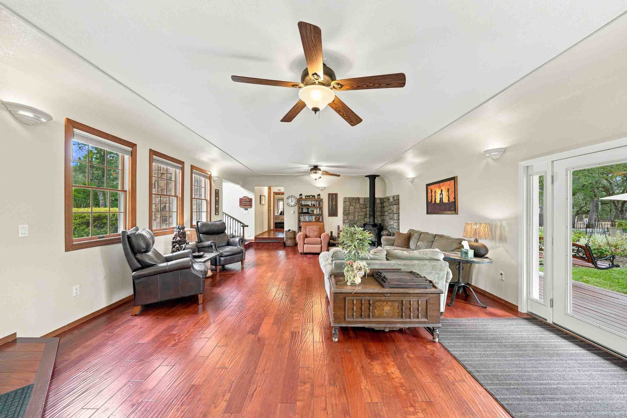 Spacious living room with hardwood floors, a wood stove, multiple seating areas, and French doors.