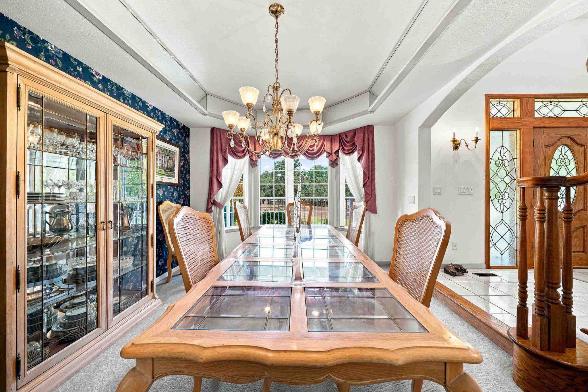 Formal dining room with a chandelier, glass-front cabinetry, and decorative wood details.