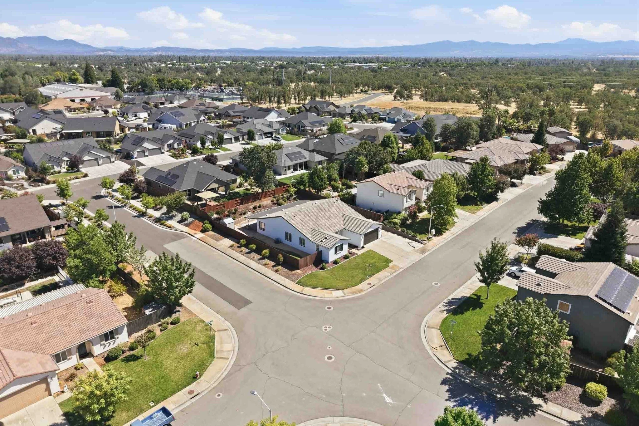 Wide aerial view of a Redding neighborhood with surrounding mountains in the distance.