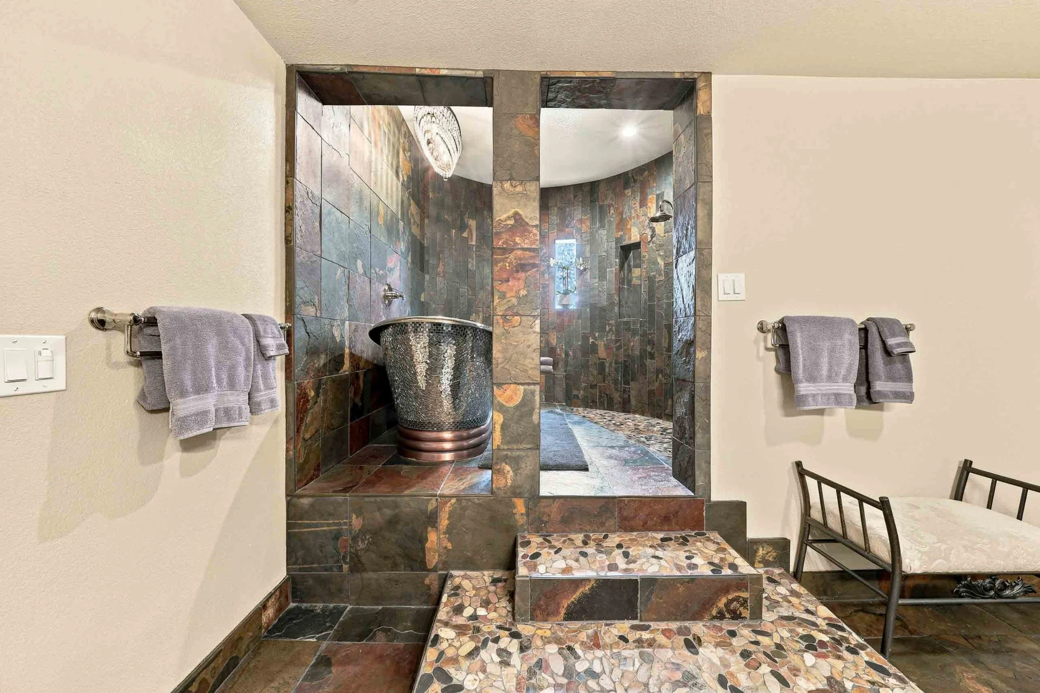 Luxury bathroom with a hammered copper soaking tub, slate tile, and a walk-in shower.