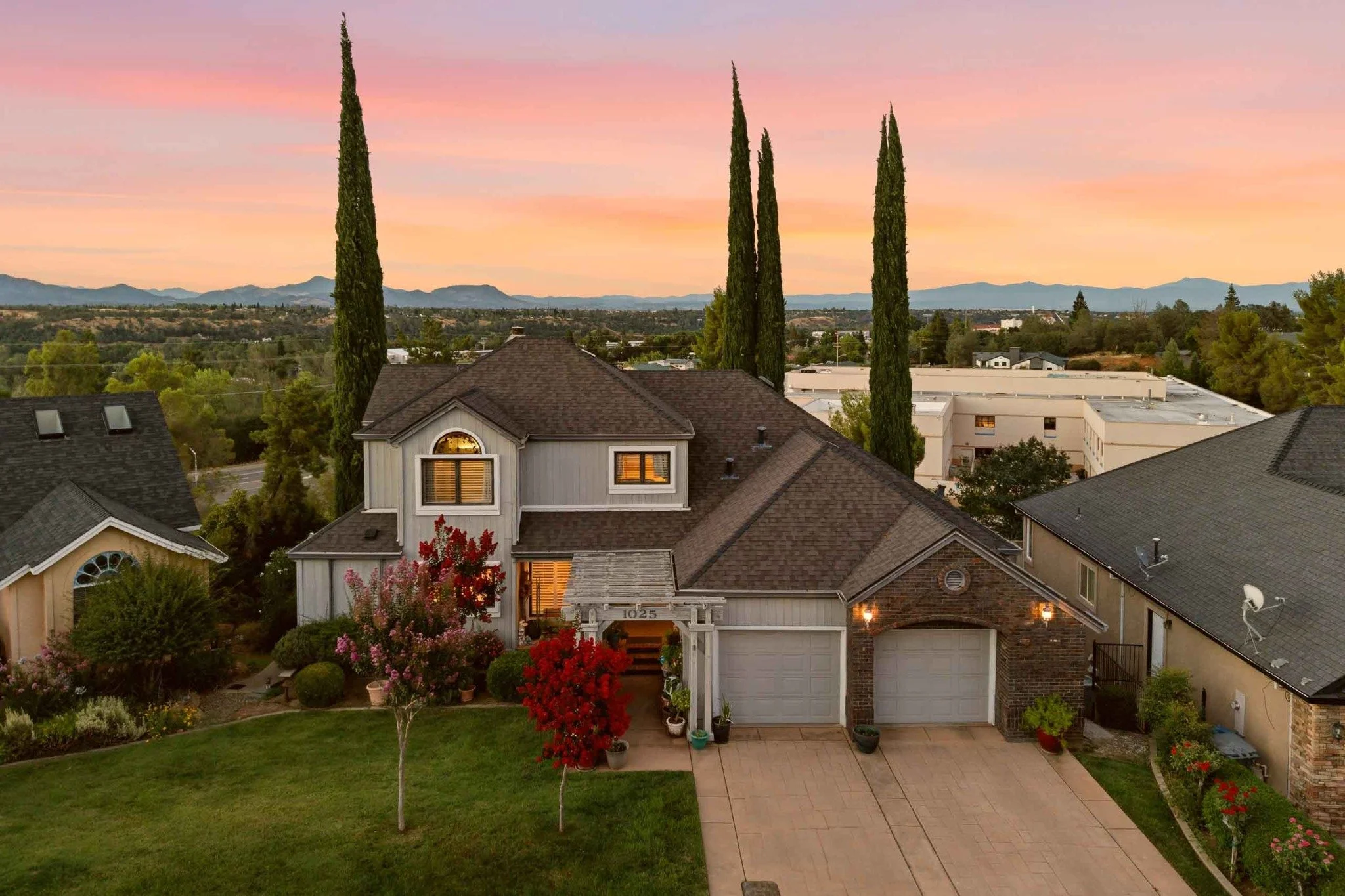 Front aerial view of a landscaped home with mountain views at twilight in Redding, California.
