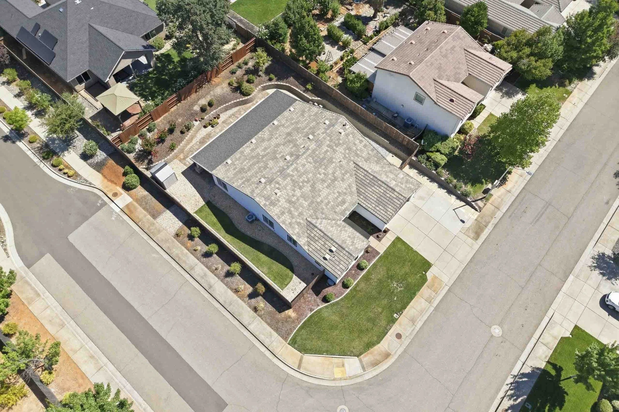 Oblique aerial view of a corner-lot home with landscaped front and side yards in Redding.