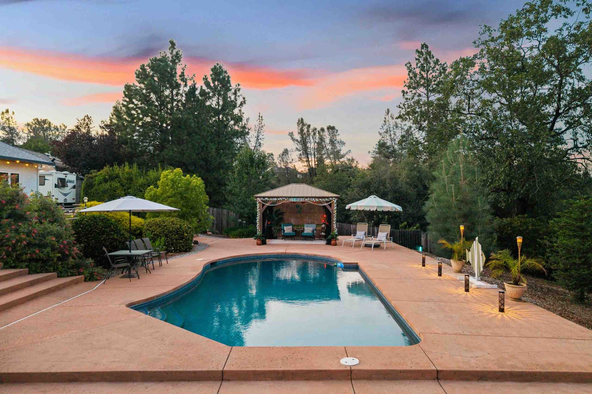 Backyard swimming pool with a gazebo and sunset sky in Redding, California.