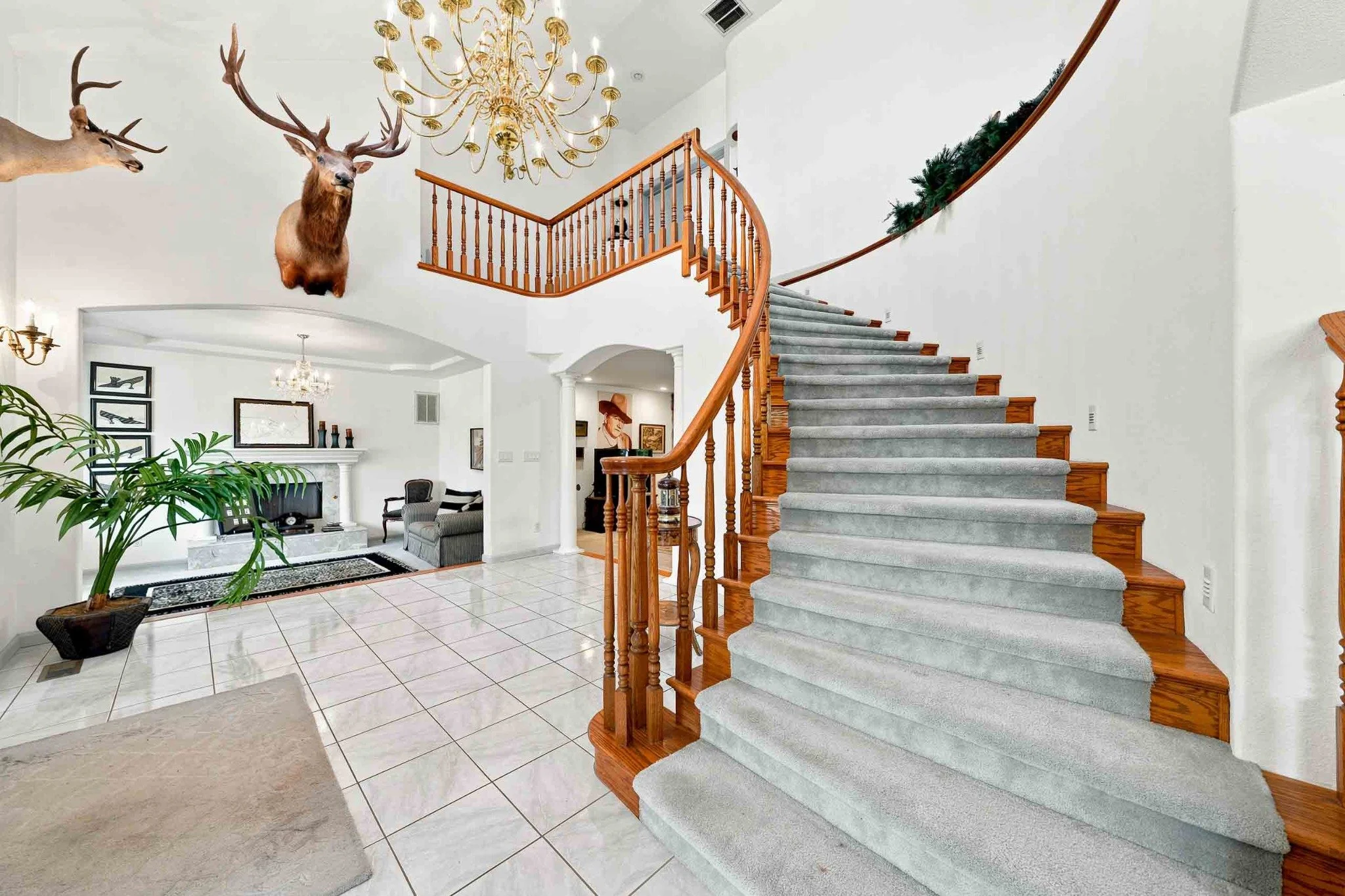 Grand entryway with a curved staircase, wood railings, chandelier, and high ceilings in a Redding home.