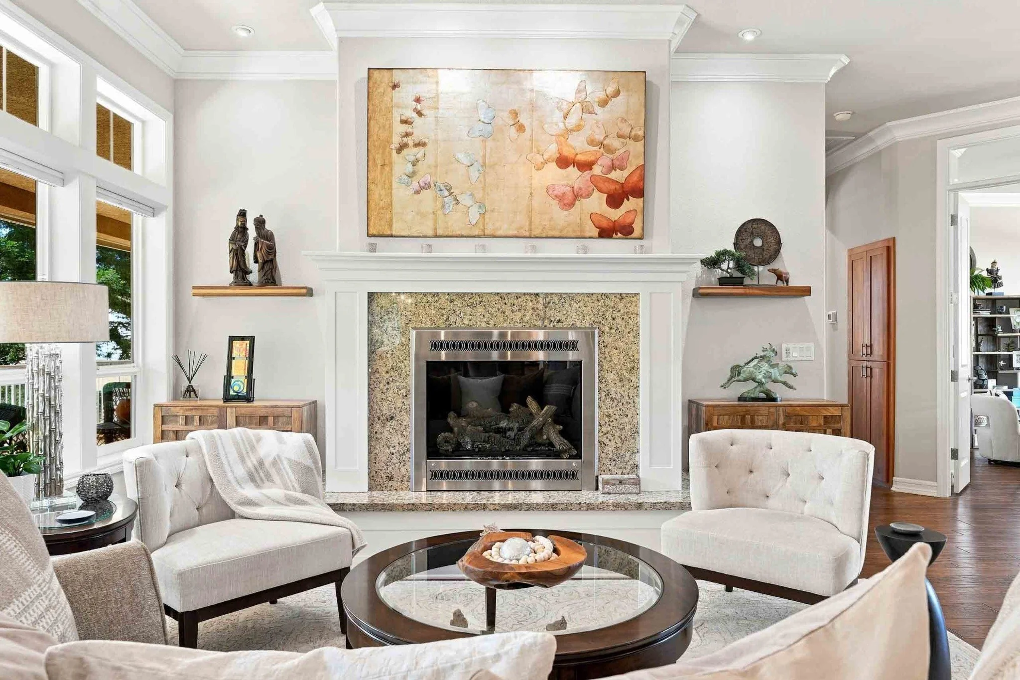 Elegant living room with a fireplace, neutral seating, crown molding, and large windows.