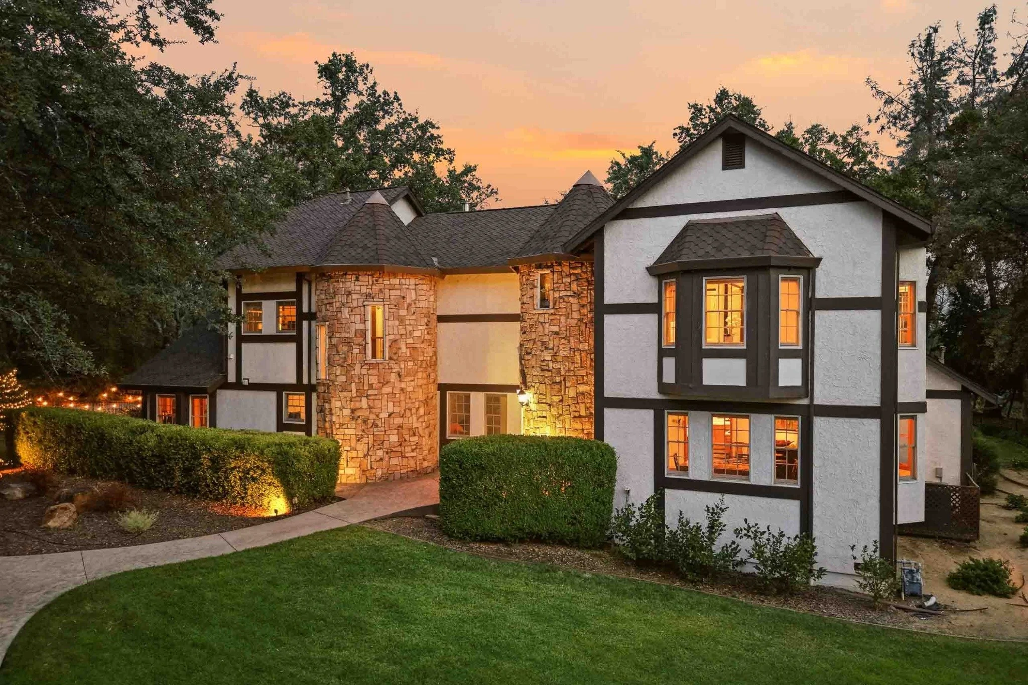 Tudor-style luxury home exterior with stone accents and illuminated windows at twilight in Redding, California.