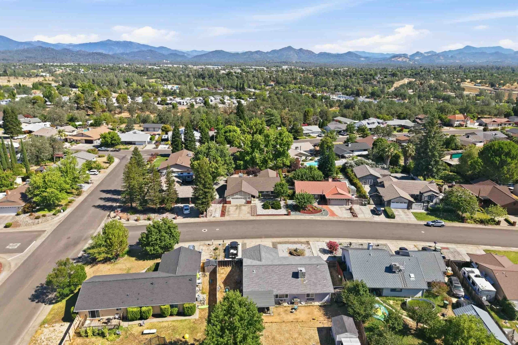Wide aerial view of a Redding neighborhood with mountain ranges in the distance.