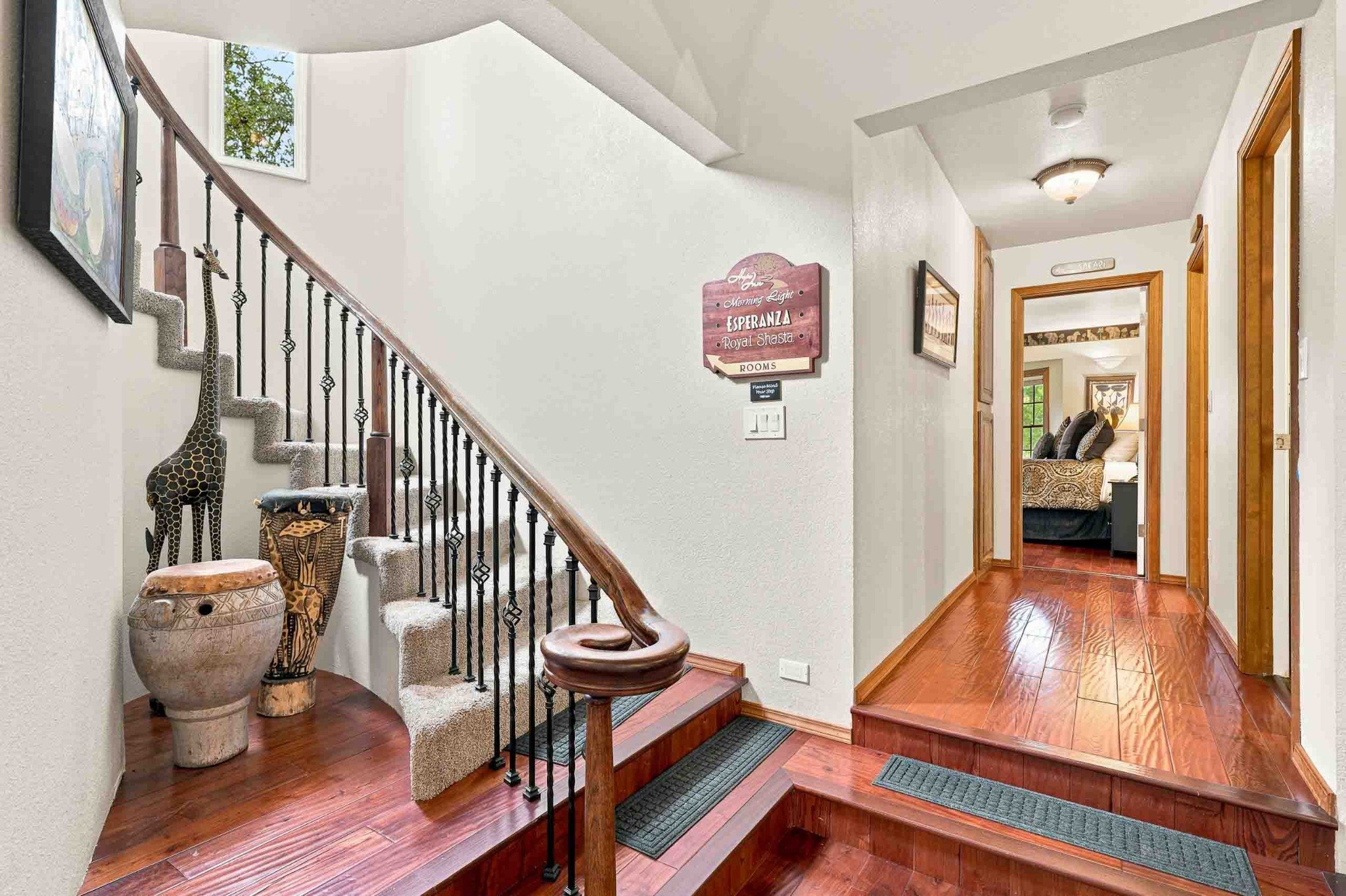 Interior hallway with a staircase, hardwood floors, and guest-room entrances in a Redding home.